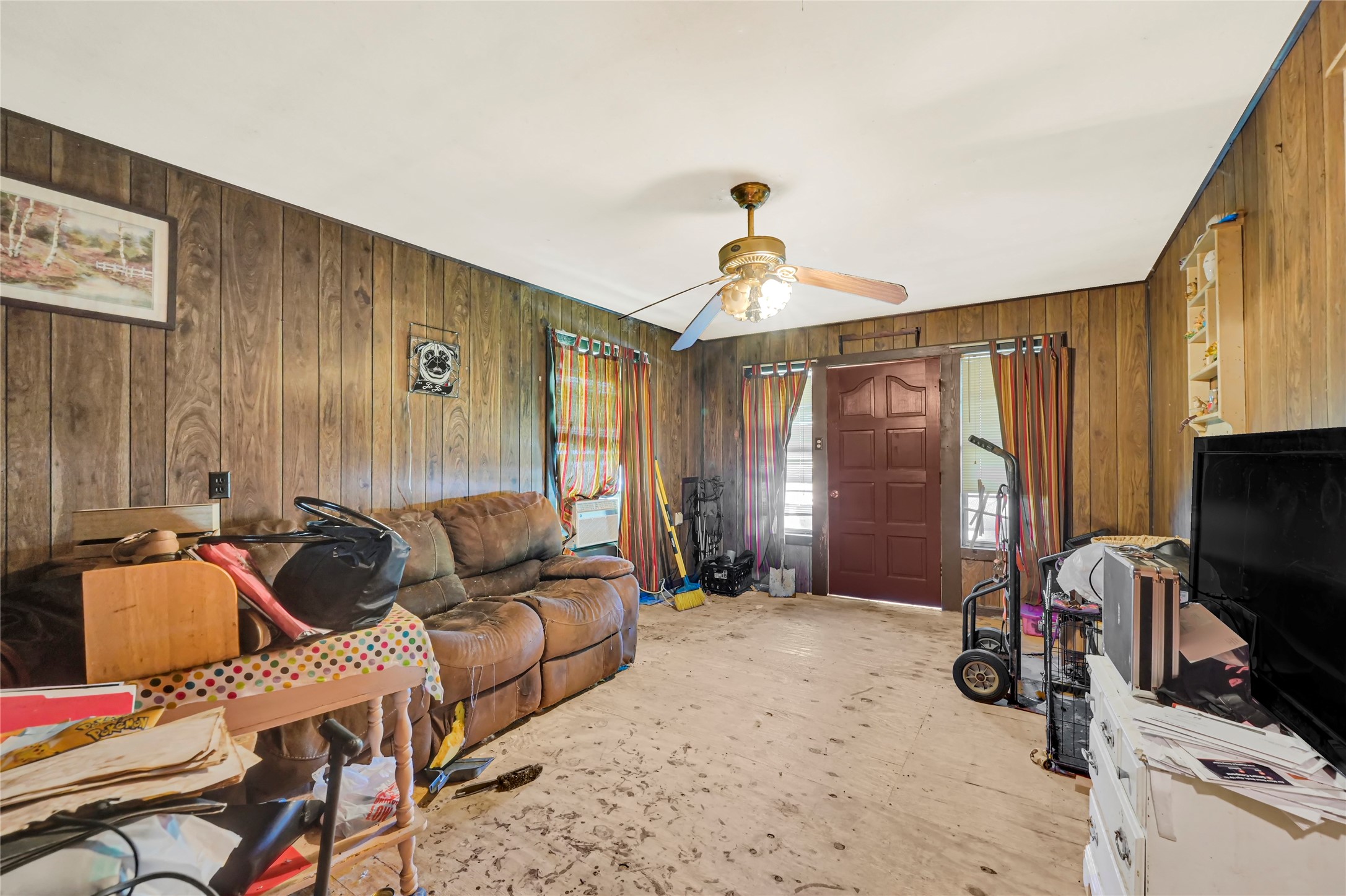 Cozy living area with wood paneling, ceiling fan, and potential for customization.