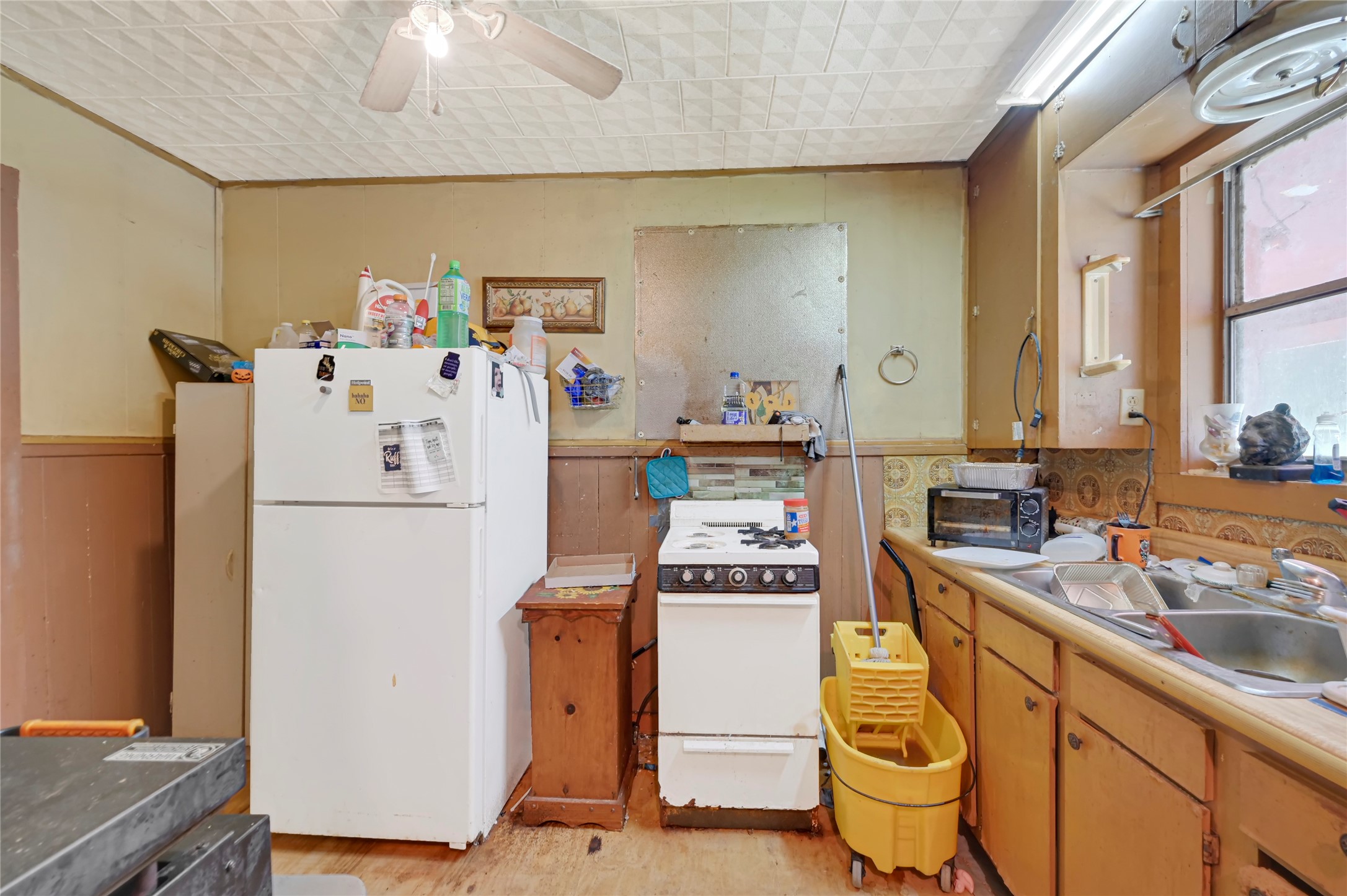 Cozy kitchen space featuring vintage cabinetry, ample storage, and natural light from a large window, offering a charming opportunity for customization and renovation.