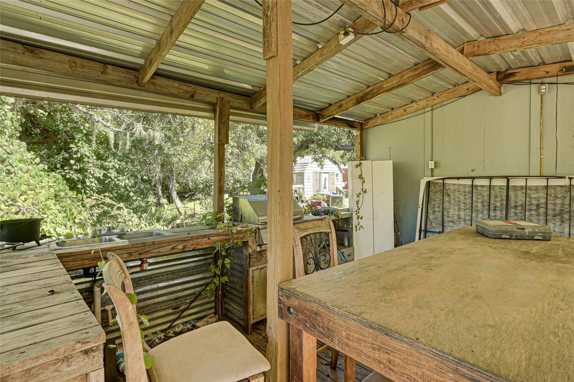 Rustic outdoor workspace with a covered seating area and views of lush greenery, perfect for creative projects or relaxation.