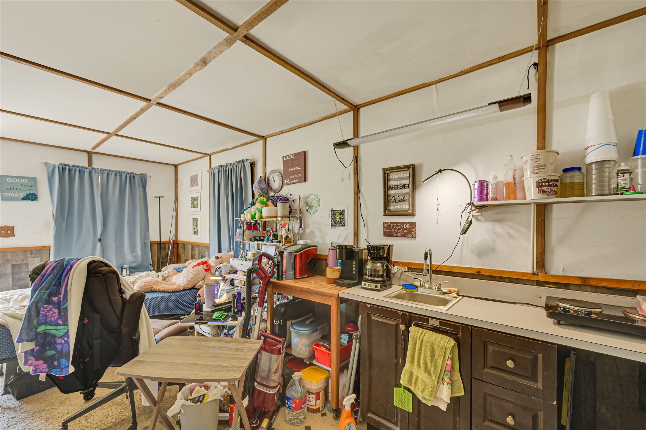 Cozy multipurpose room featuring a compact kitchenette, ample shelving, and a comfortable seating area, perfect for relaxation or hobbies.