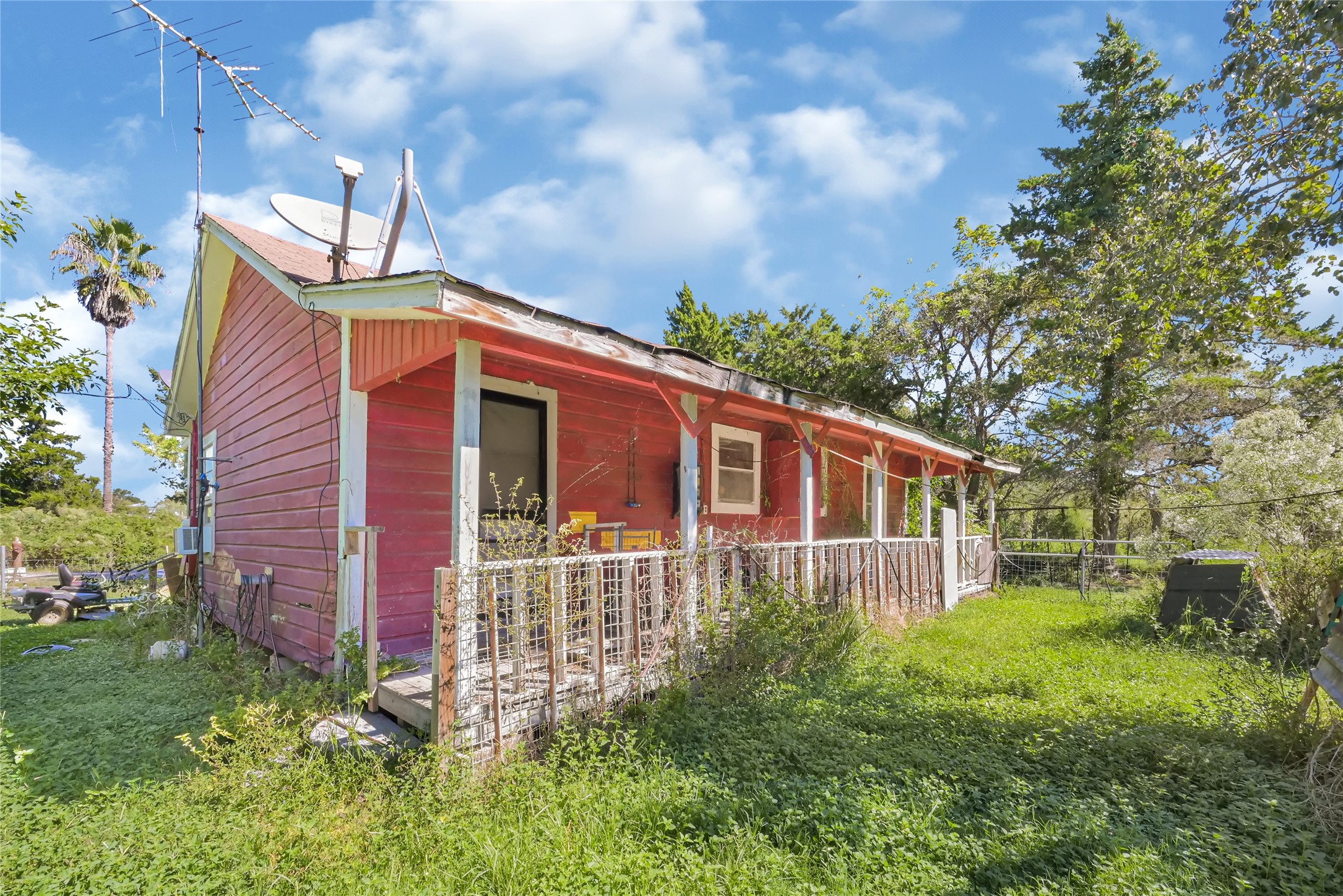Charming rustic home with a vibrant exterior, spacious porch, and surrounded by lush greenery, offering a serene retreat.