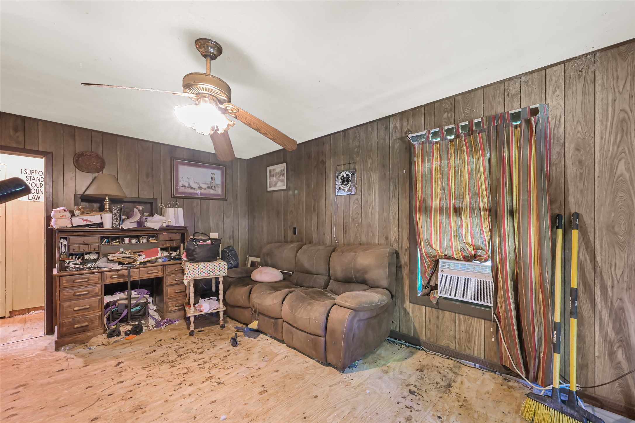 Cozy room featuring wood paneling, a comfortable recliner sofa, and a ceiling fan, offering a rustic charm.