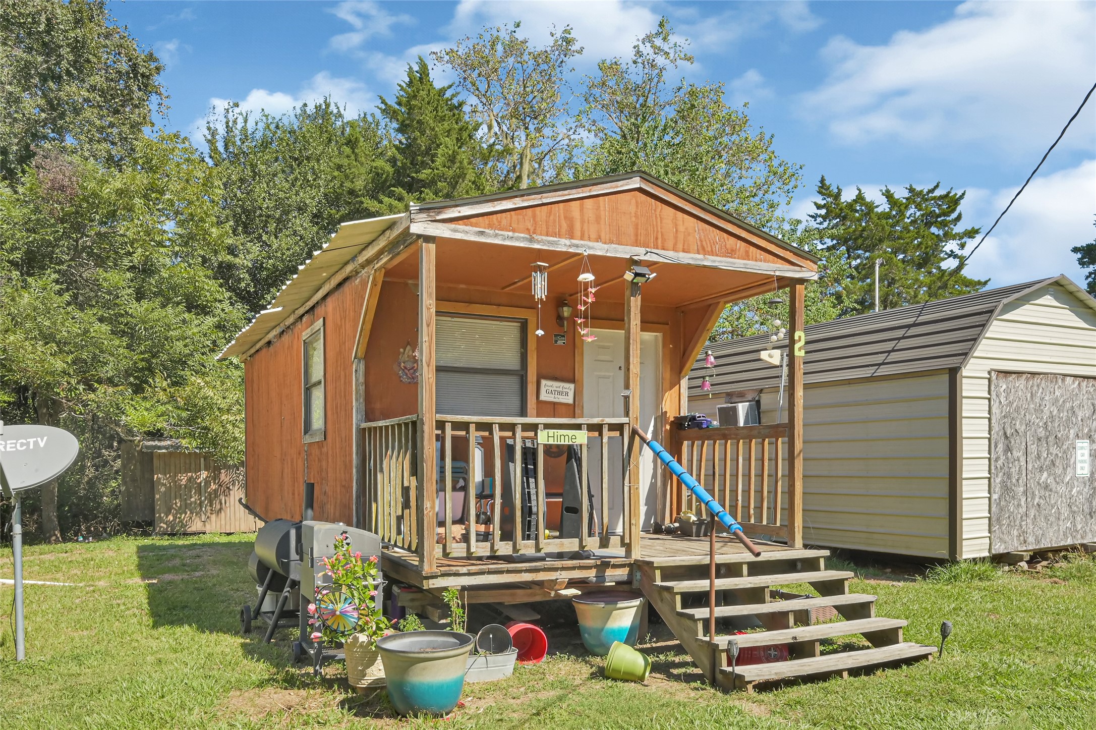 Charming small cabin with a cozy front porch, nestled in a lush, green setting. Ideal for a peaceful retreat.
