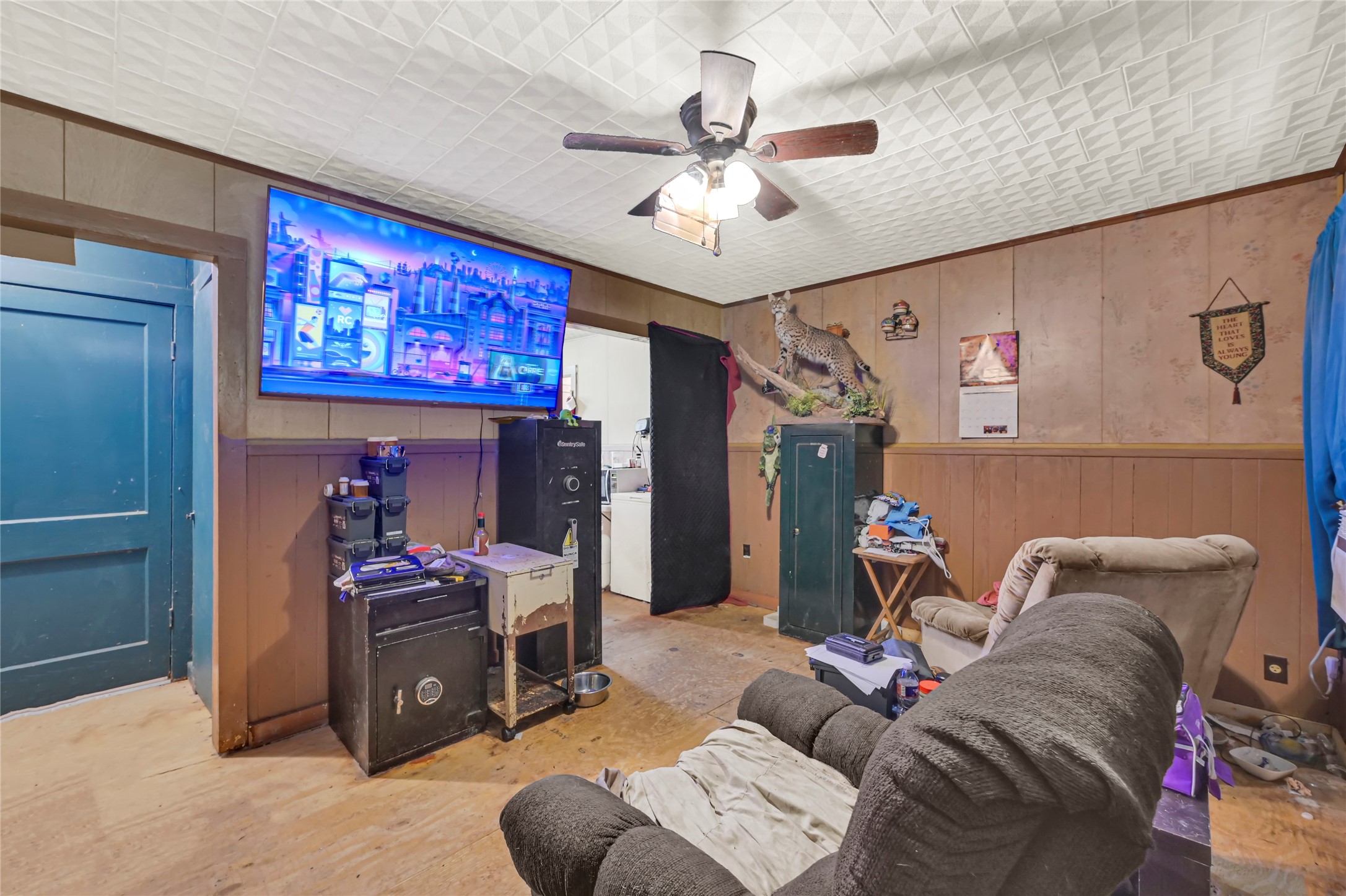 Cozy entertainment room featuring a mounted TV, comfortable seating, and wood panel walls, perfect for relaxing or gaming.