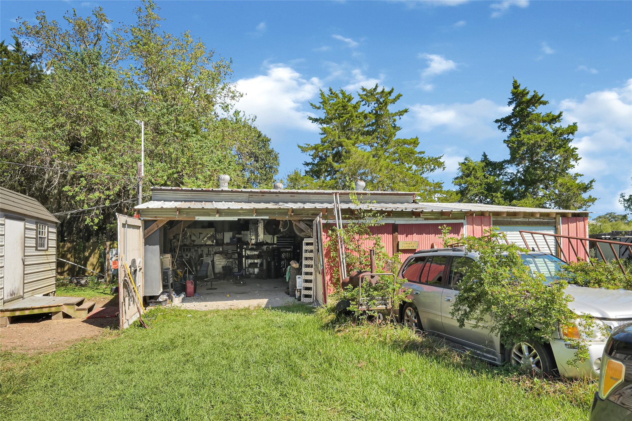 Spacious outdoor workshop with ample storage, surrounded by lush greenery and mature trees, perfect for projects and creativity.