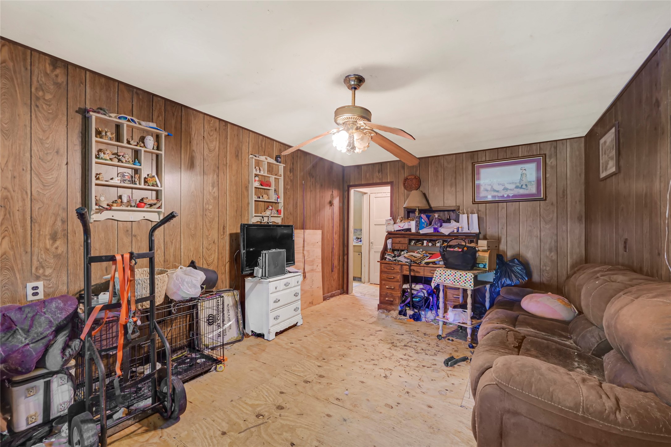 Cozy living space with wood paneling, ceiling fan, and potential for customization.