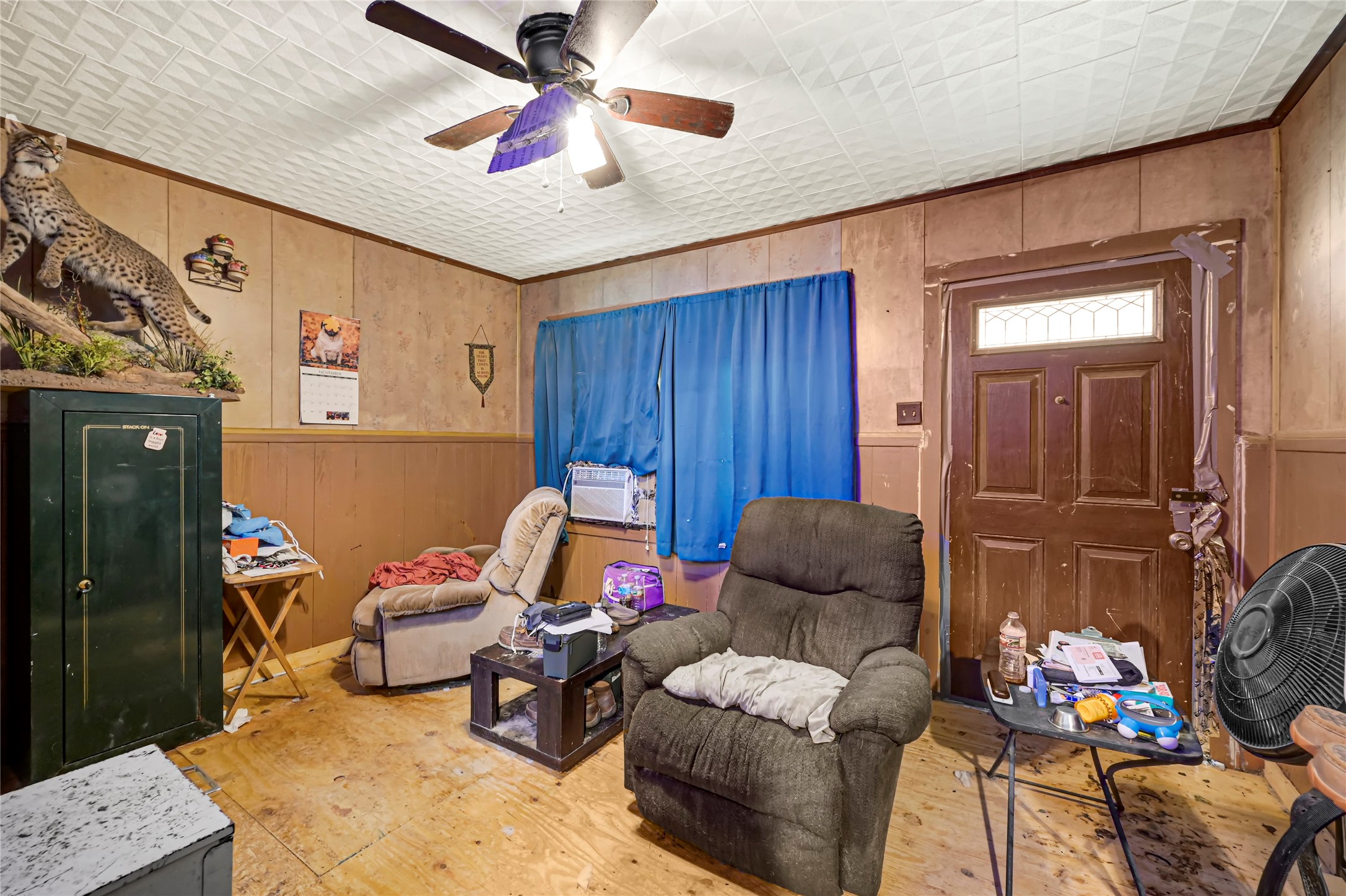 Cozy living space featuring wood paneling, a ceiling fan, and comfortable seating, perfect for relaxation.