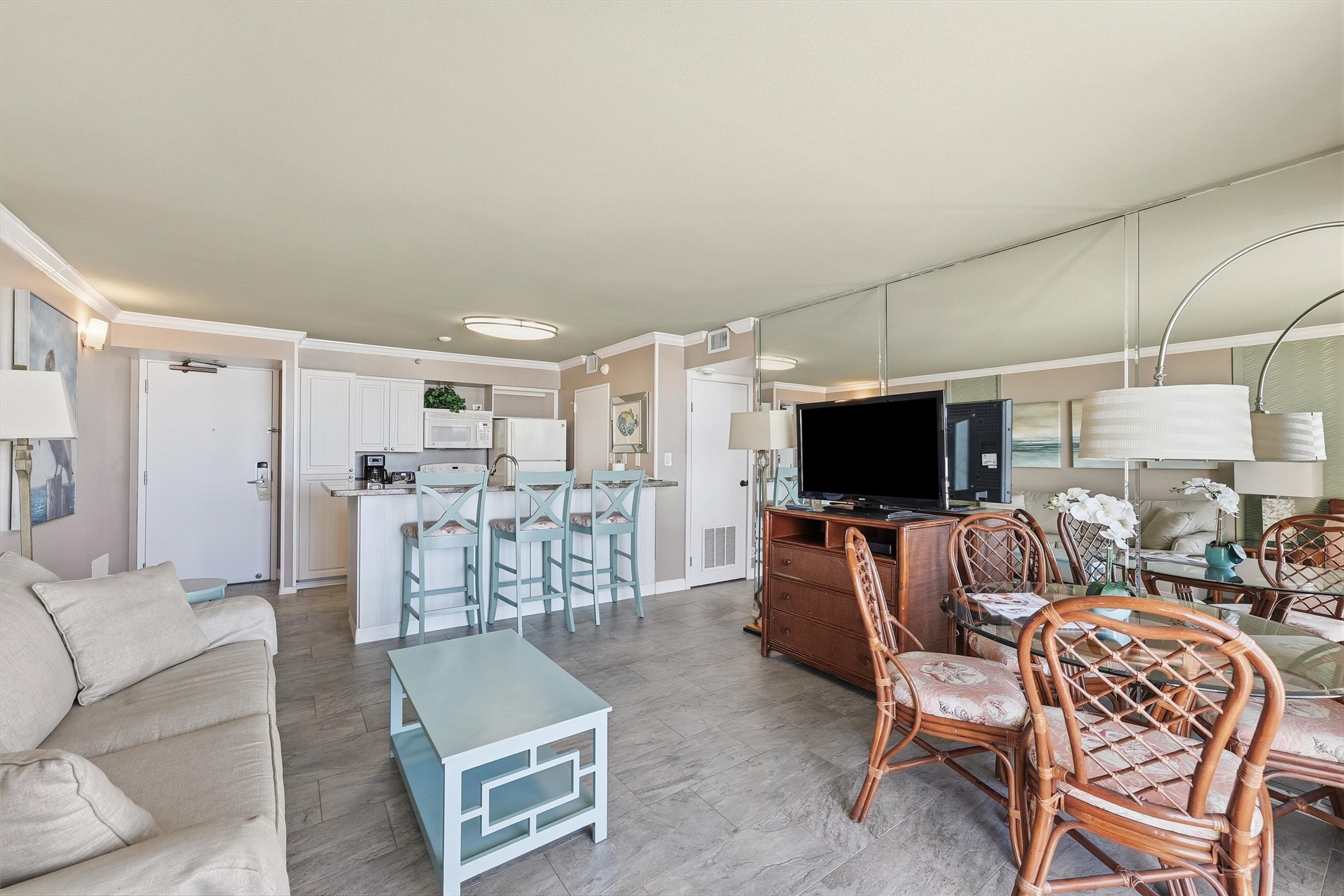 The connected living and dining spaces offer an inviting setting for entertaining, enhanced by a mirrored accent wall.