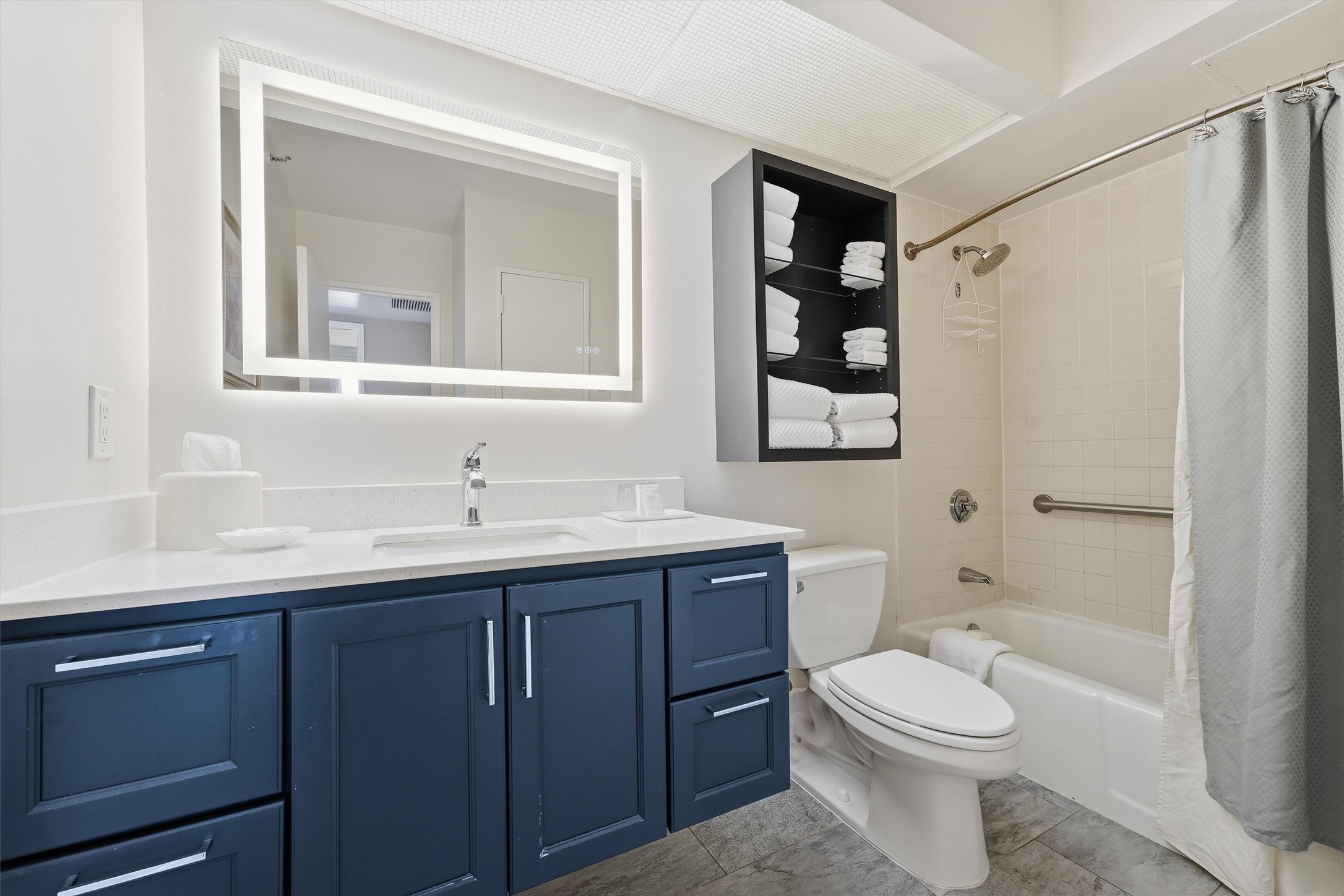 The bathroom features a spacious vanity, illuminated mirror, and a versatile tub/shower combination.