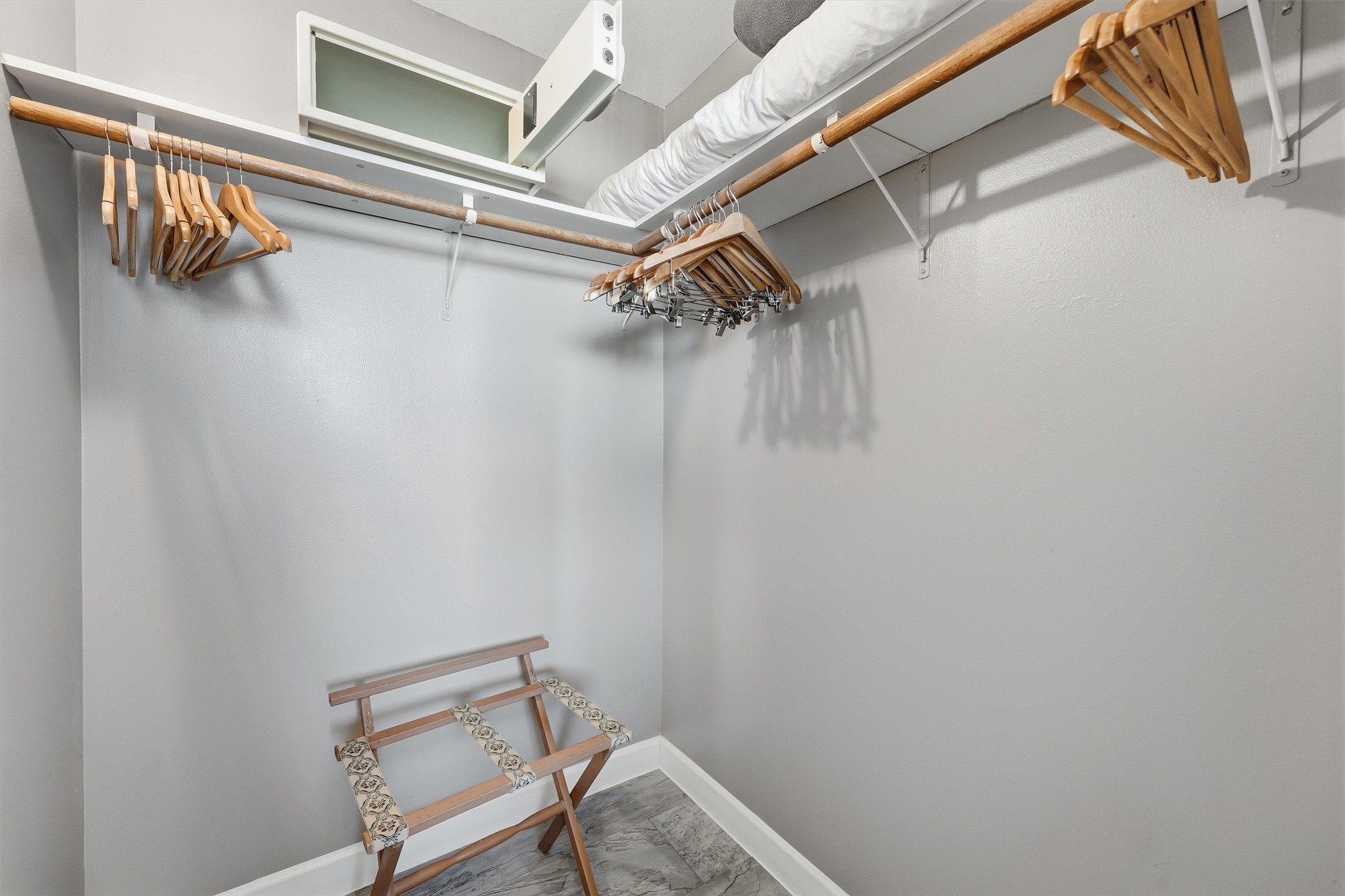 A walk-in closet offers wraparound hanging space and upper shelving for convenient storage.