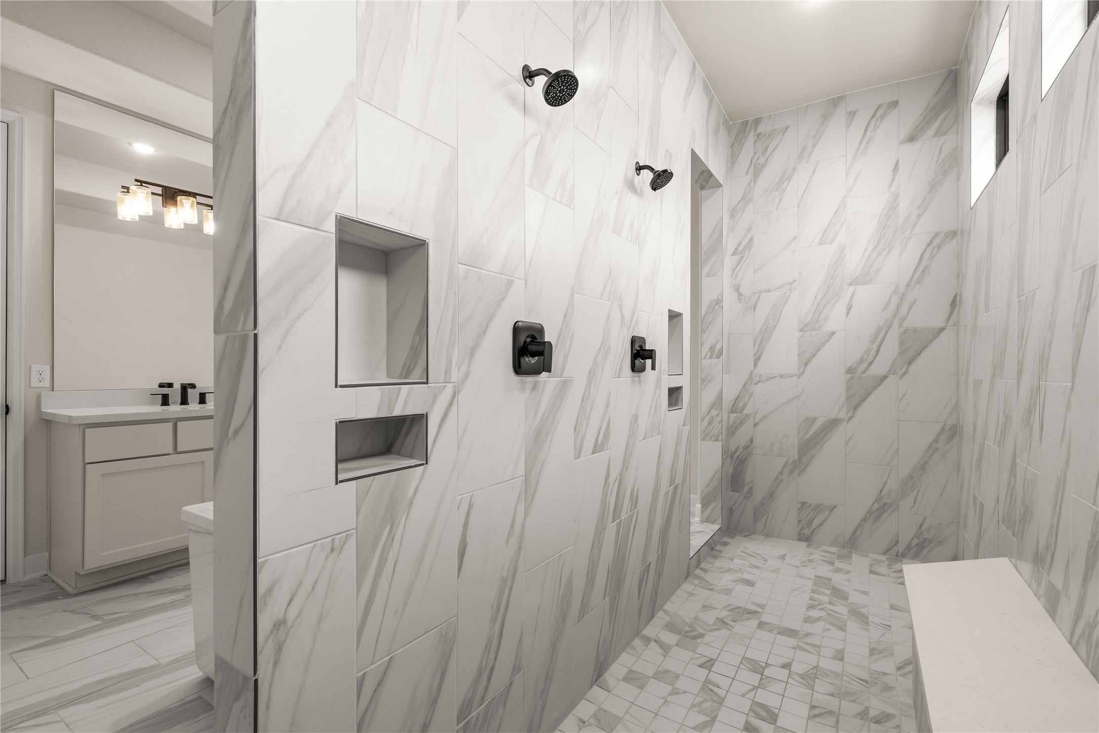 Luxurious walk-in shower featuring elegant marble, dual showerheads, built-in niches, and a sleek bench for ultimate relaxation.