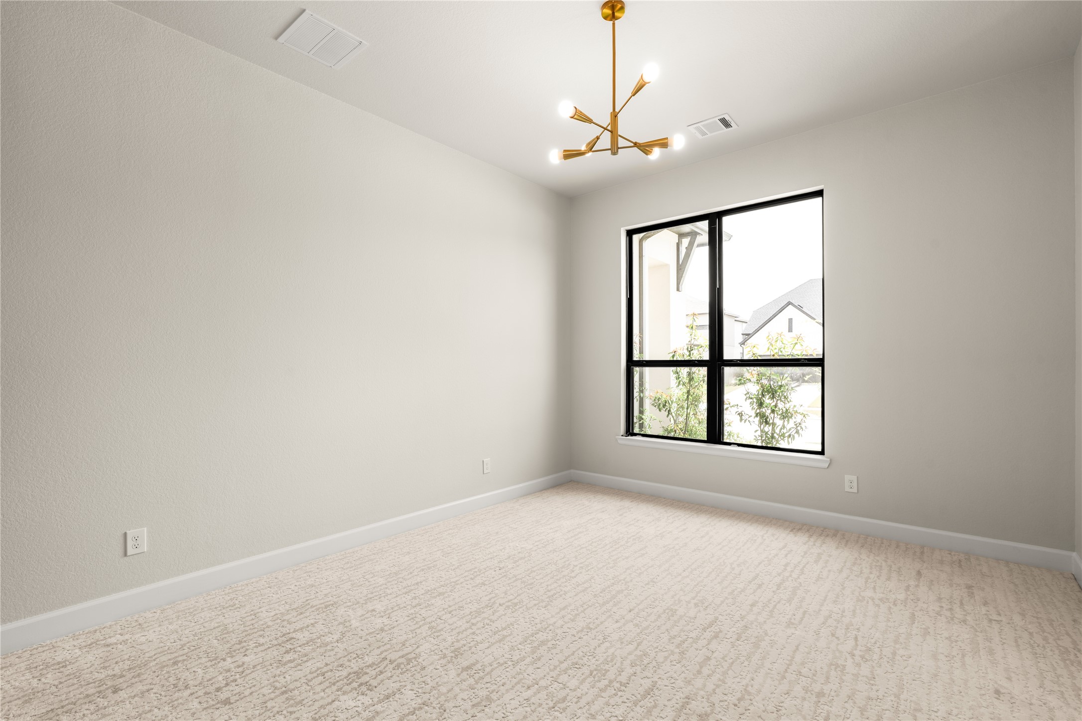 Bright and airy secondary bedroom featuring a modern light fixture and a large window that invites natural light, complemented by soft carpet flooring and neutral walls.