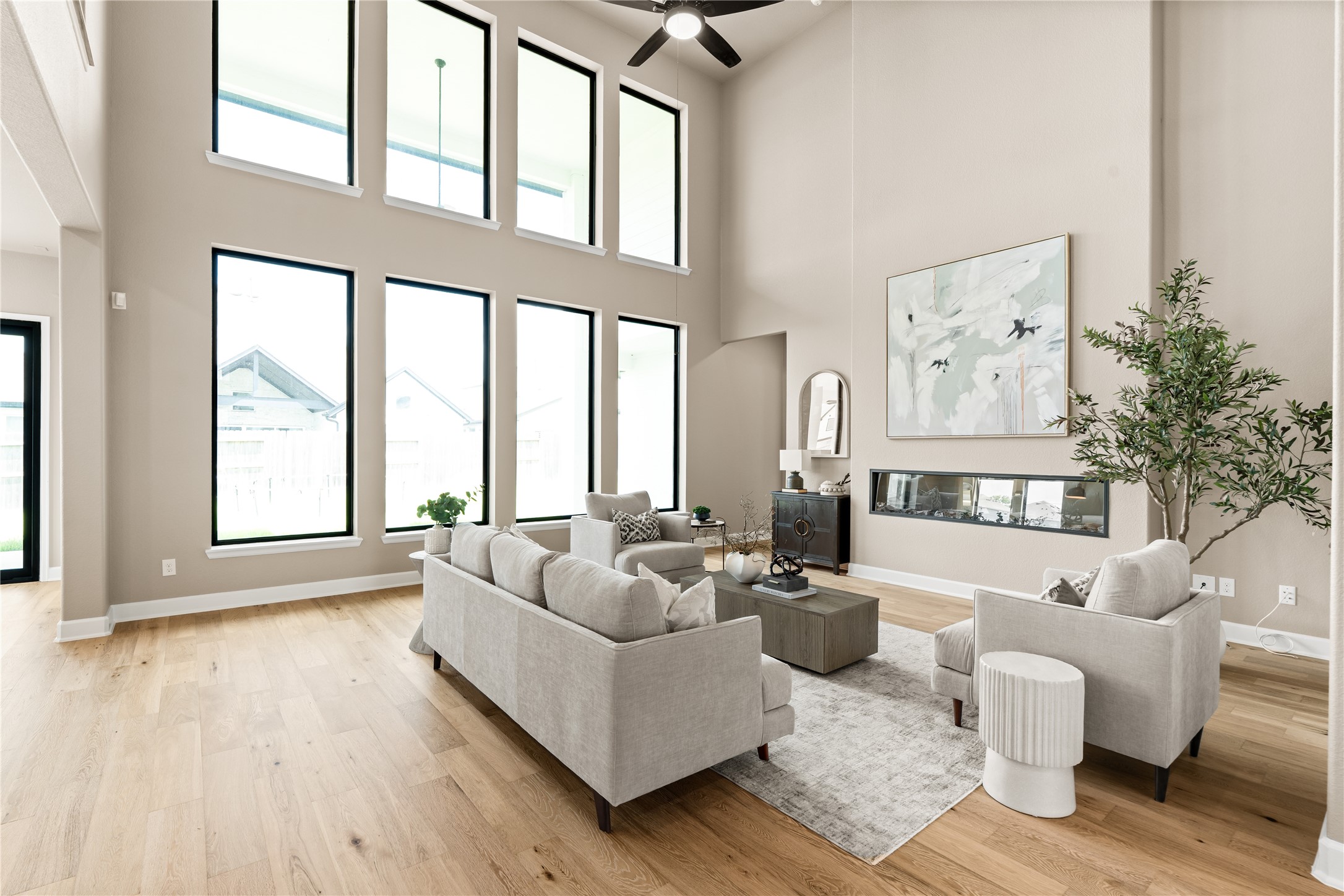 Stunning living room with soaring ceilings, expansive windows for natural light, and a modern fireplace accentuating the open space. *Virtually Staged*