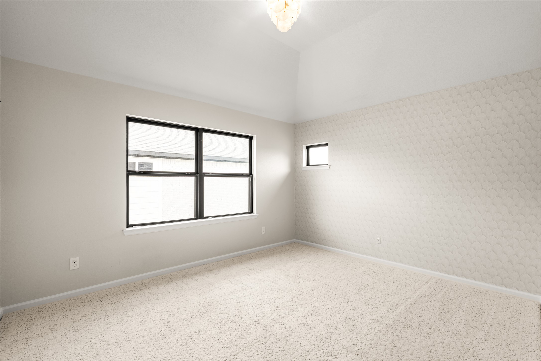 Bright and spacious bedroom with soft carpet, neutral tones, and ample natural light from large windows.