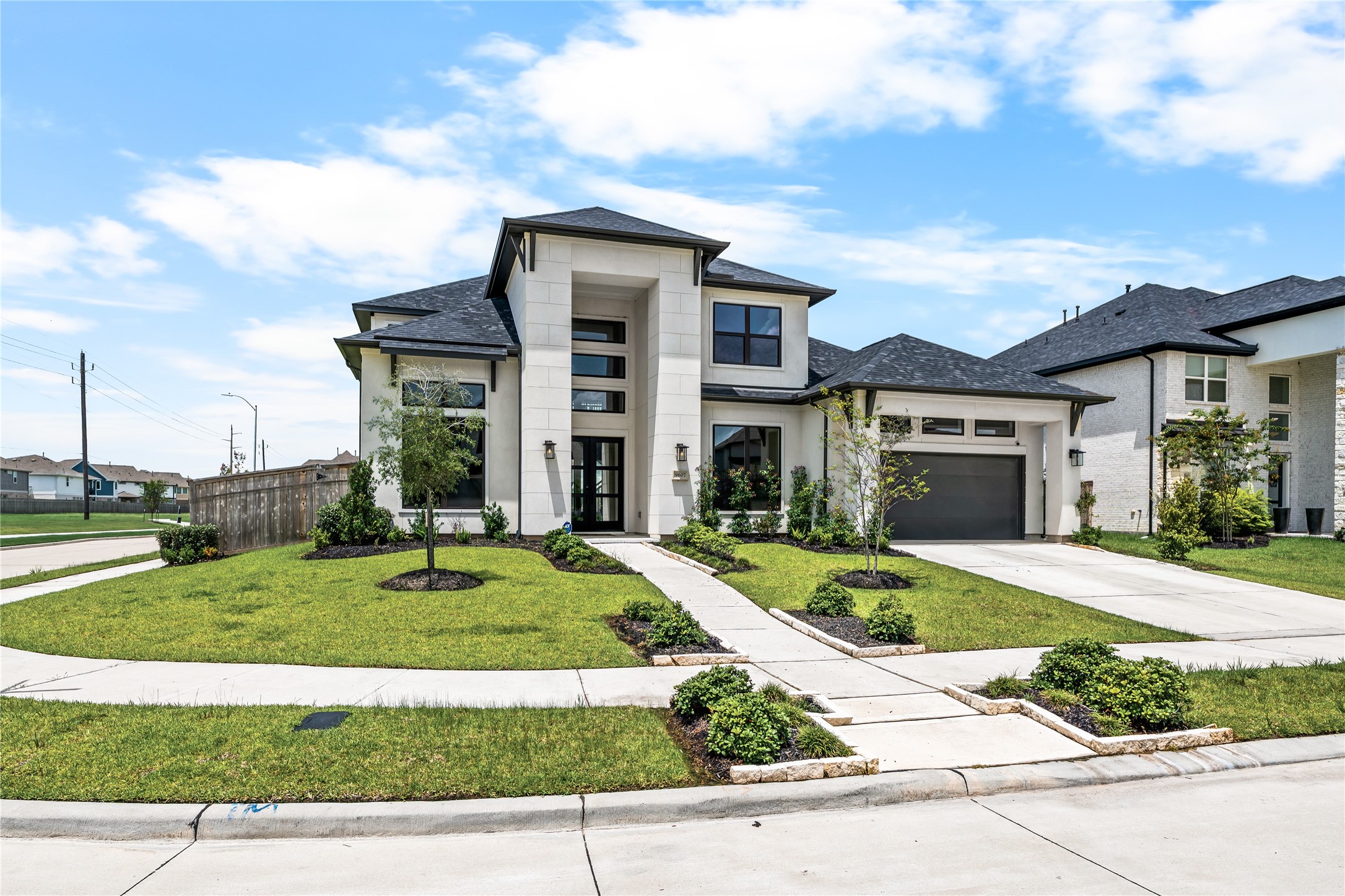 Stunning modern two-story home with sleek architectural design, expansive windows, and a manicured front yard, situated in a desirable neighborhood.