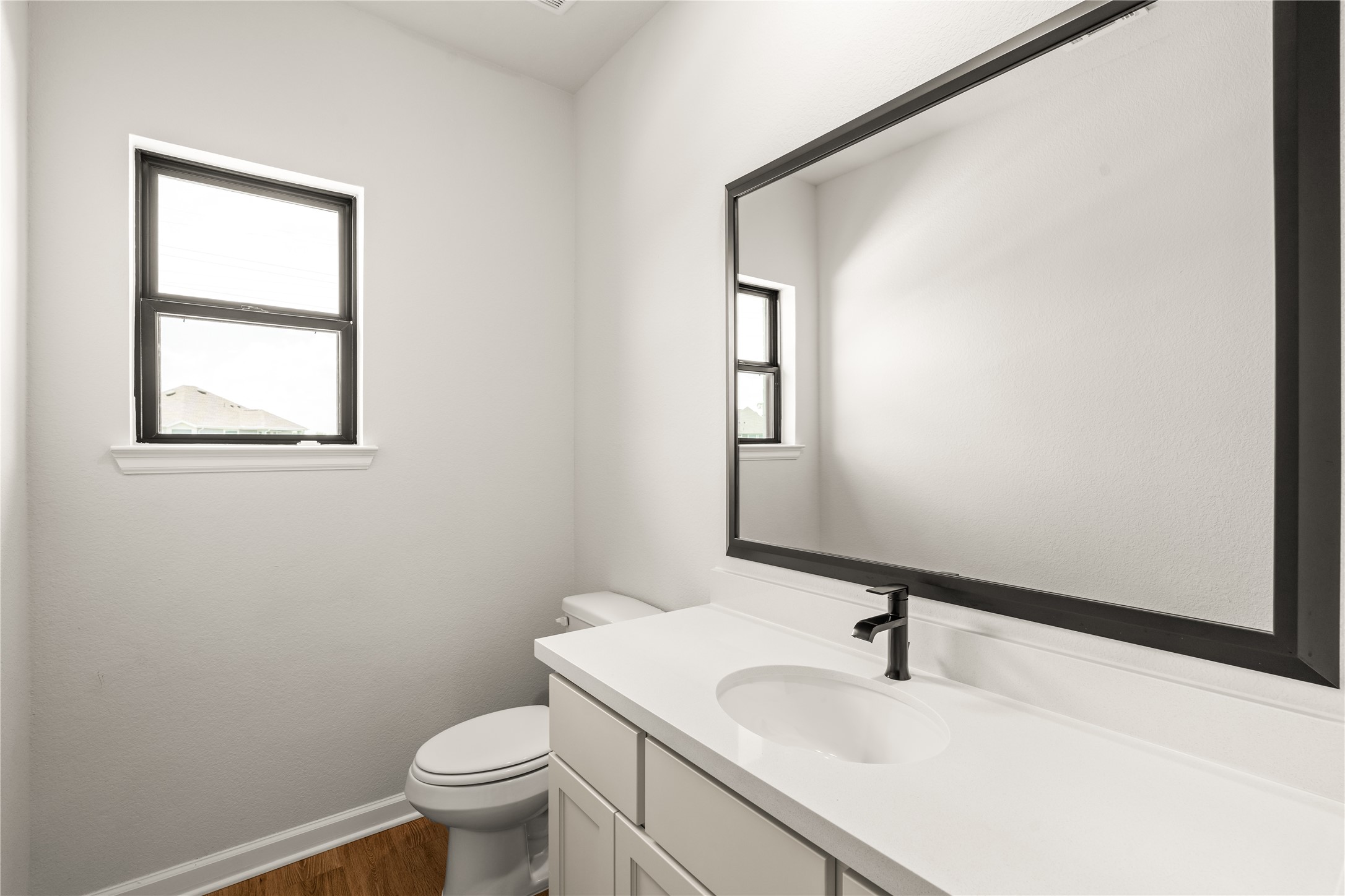 Bright and modern bathroom featuring sleek fixtures and a large mirror. Perfect for guests!