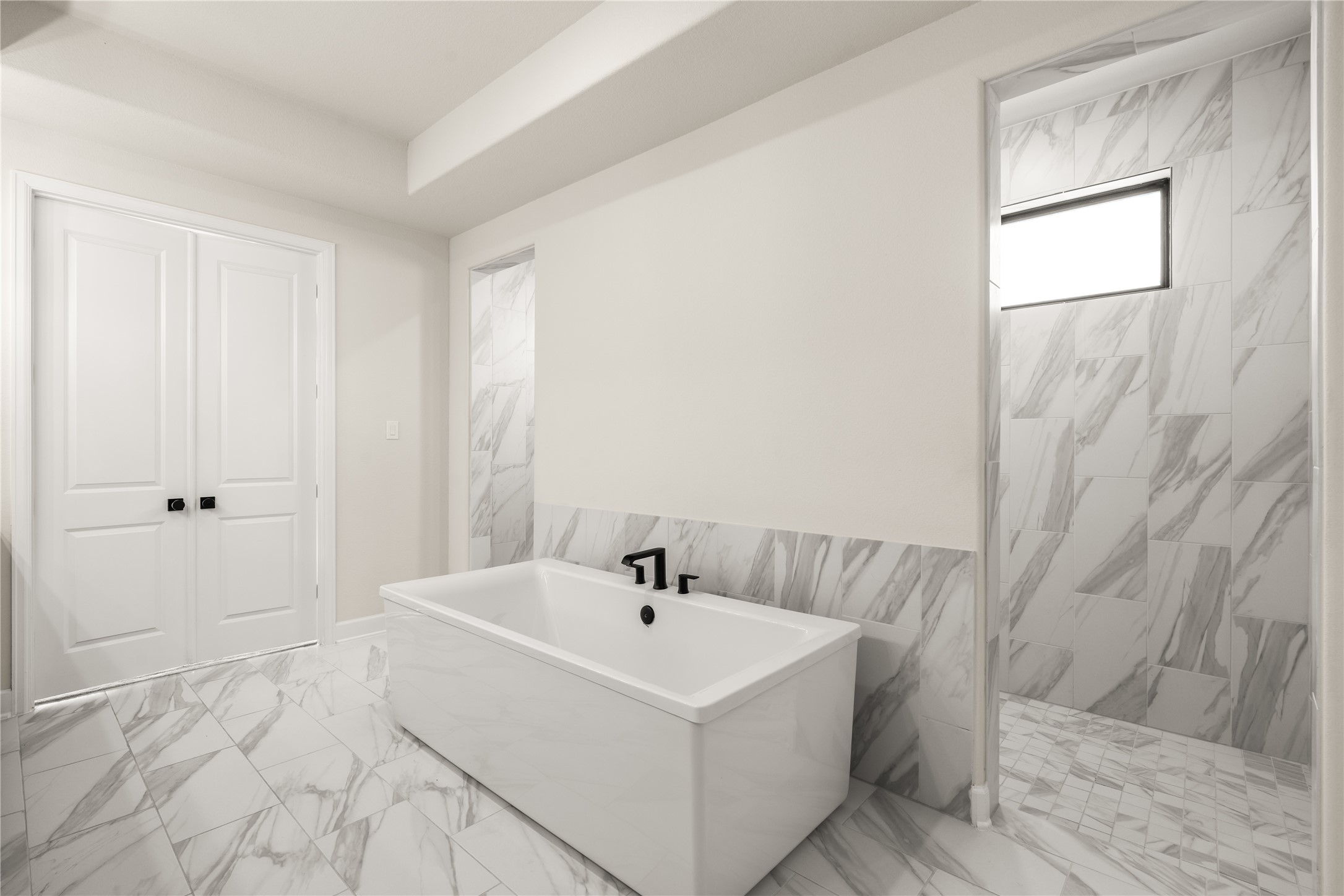 Opulent bathroom featuring a sleek freestanding tub, elegant marble, and a spacious walk-in shower, offering a spa-like retreat after a long day.