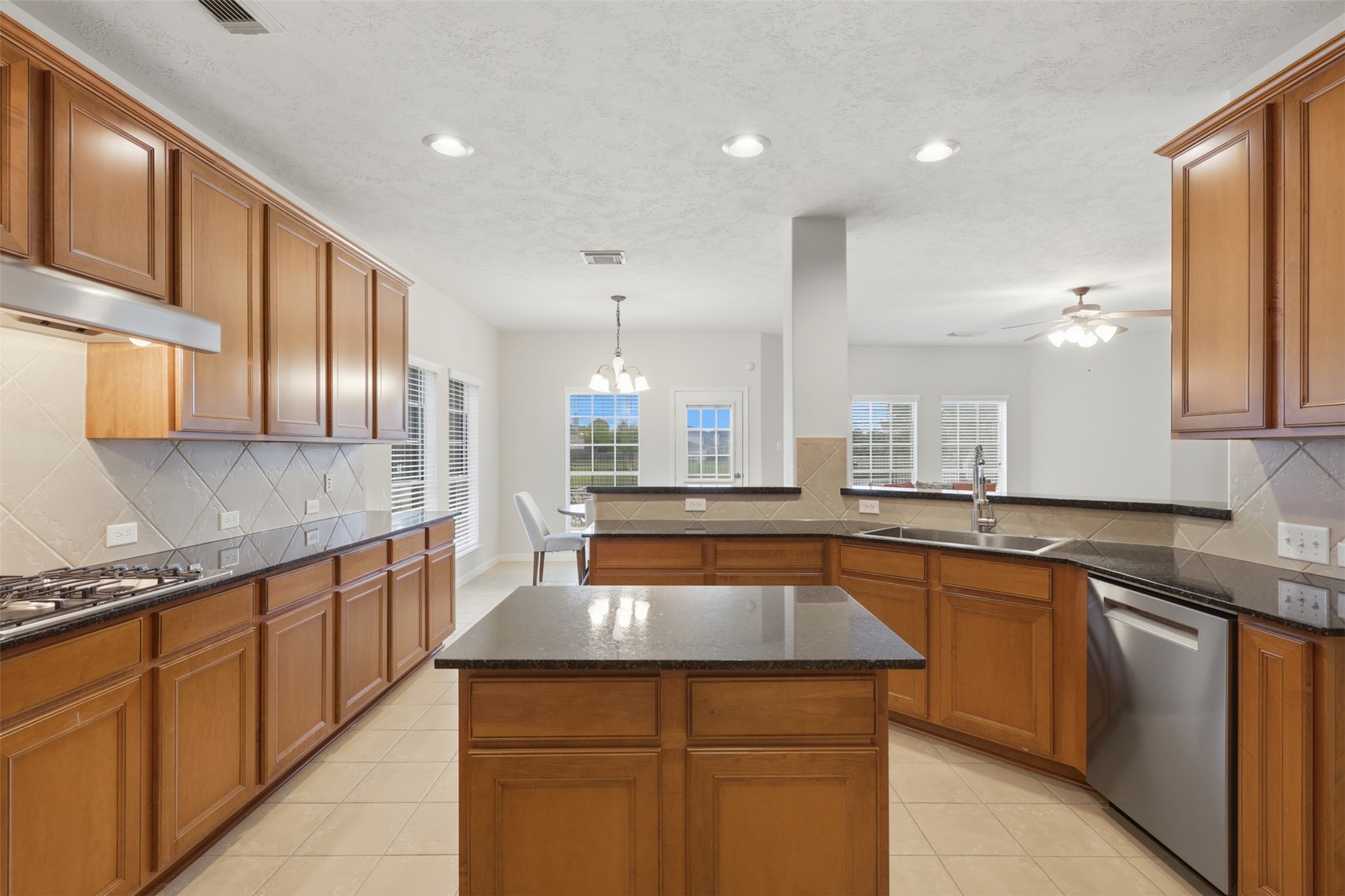 The generous kitchen features abundant cabinetry, granite countertops, a center island, recessed lighting, and an open layout.