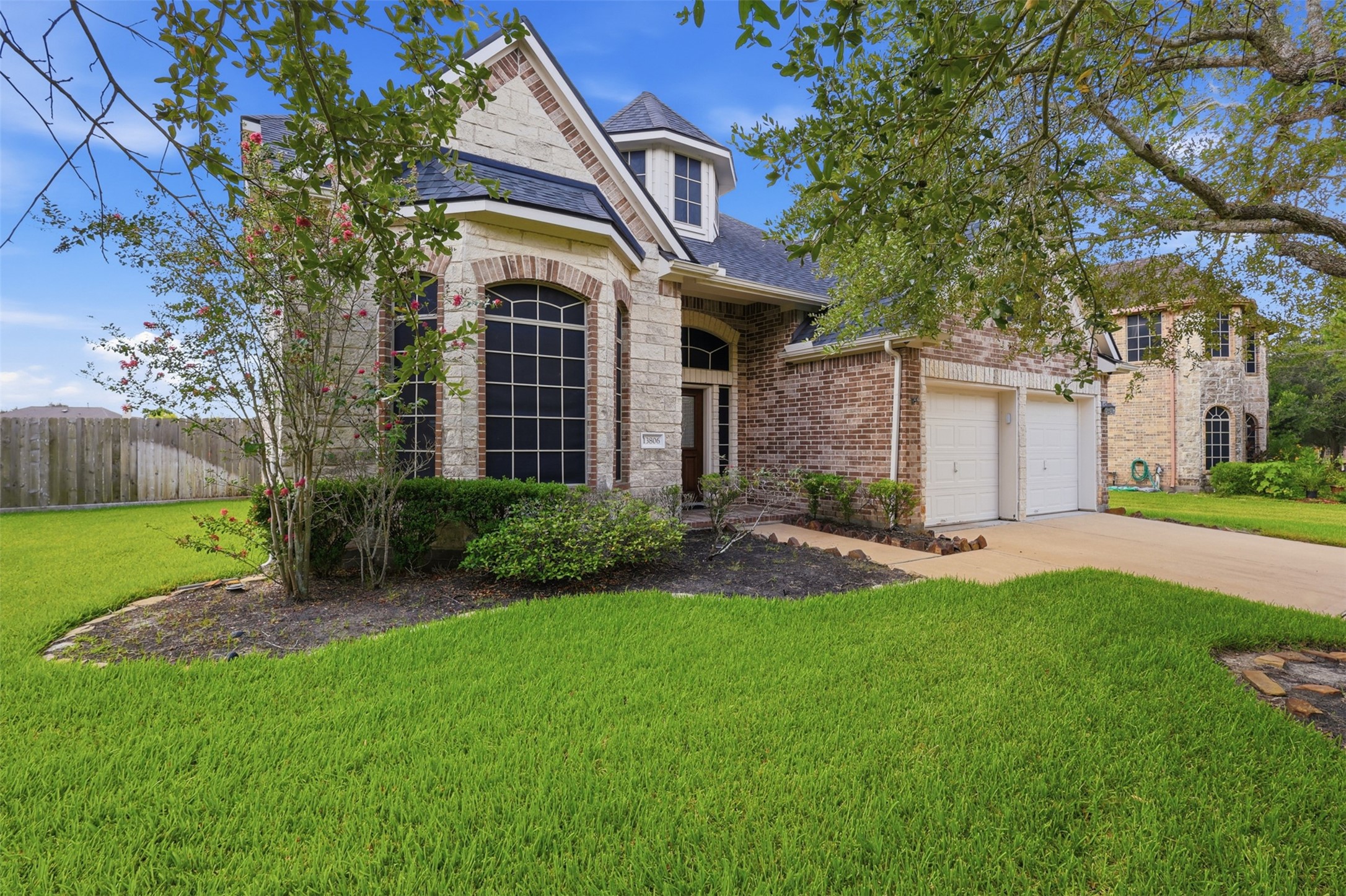 Stone and brick detailing, dramatic arched windows, and mature landscaping create a distinctive and polished front exterior.