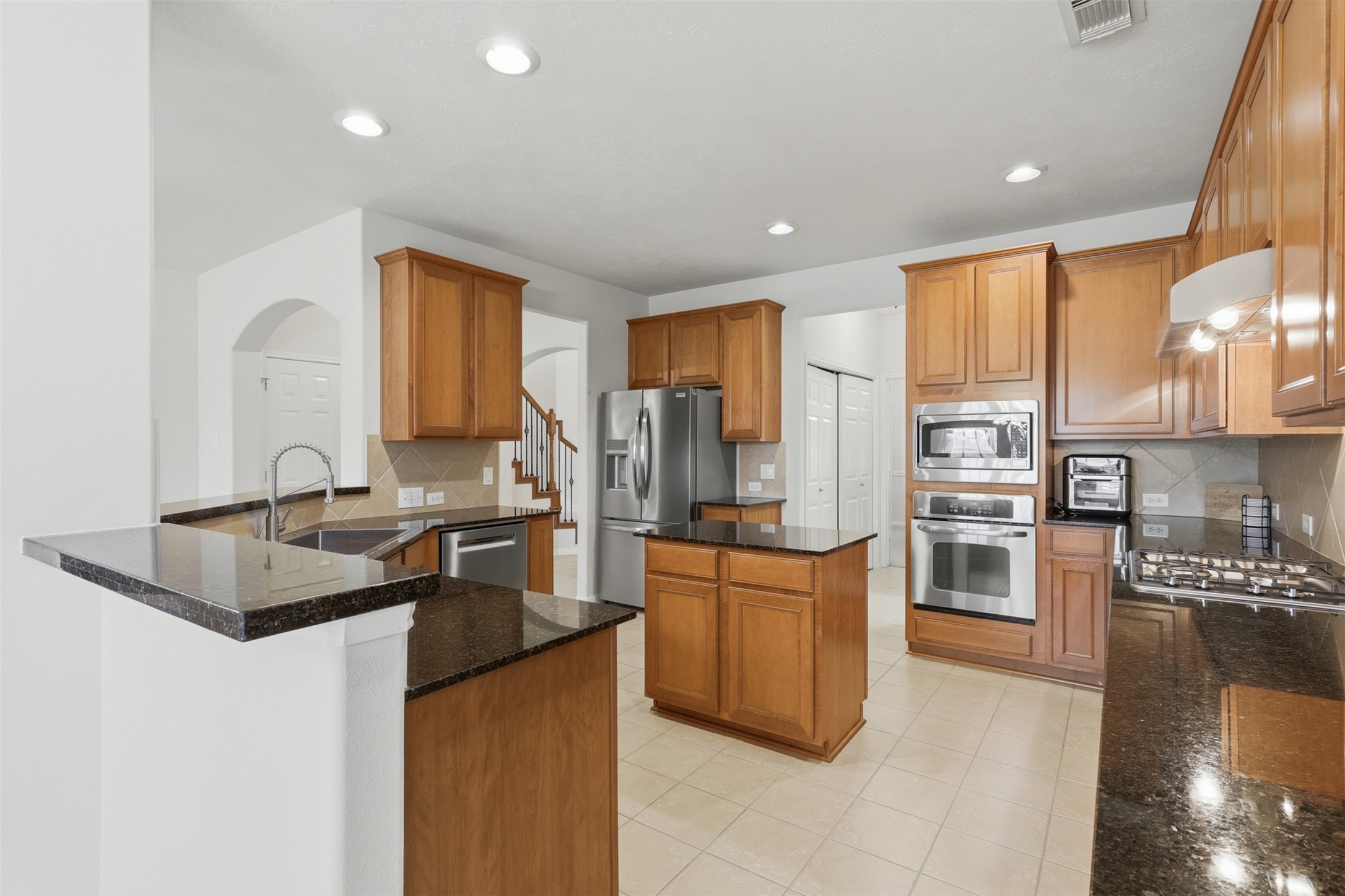 This well-equipped kitchen offers a center island, breakfast bar, stainless steel appliances, and plentiful counter and cabinet space.