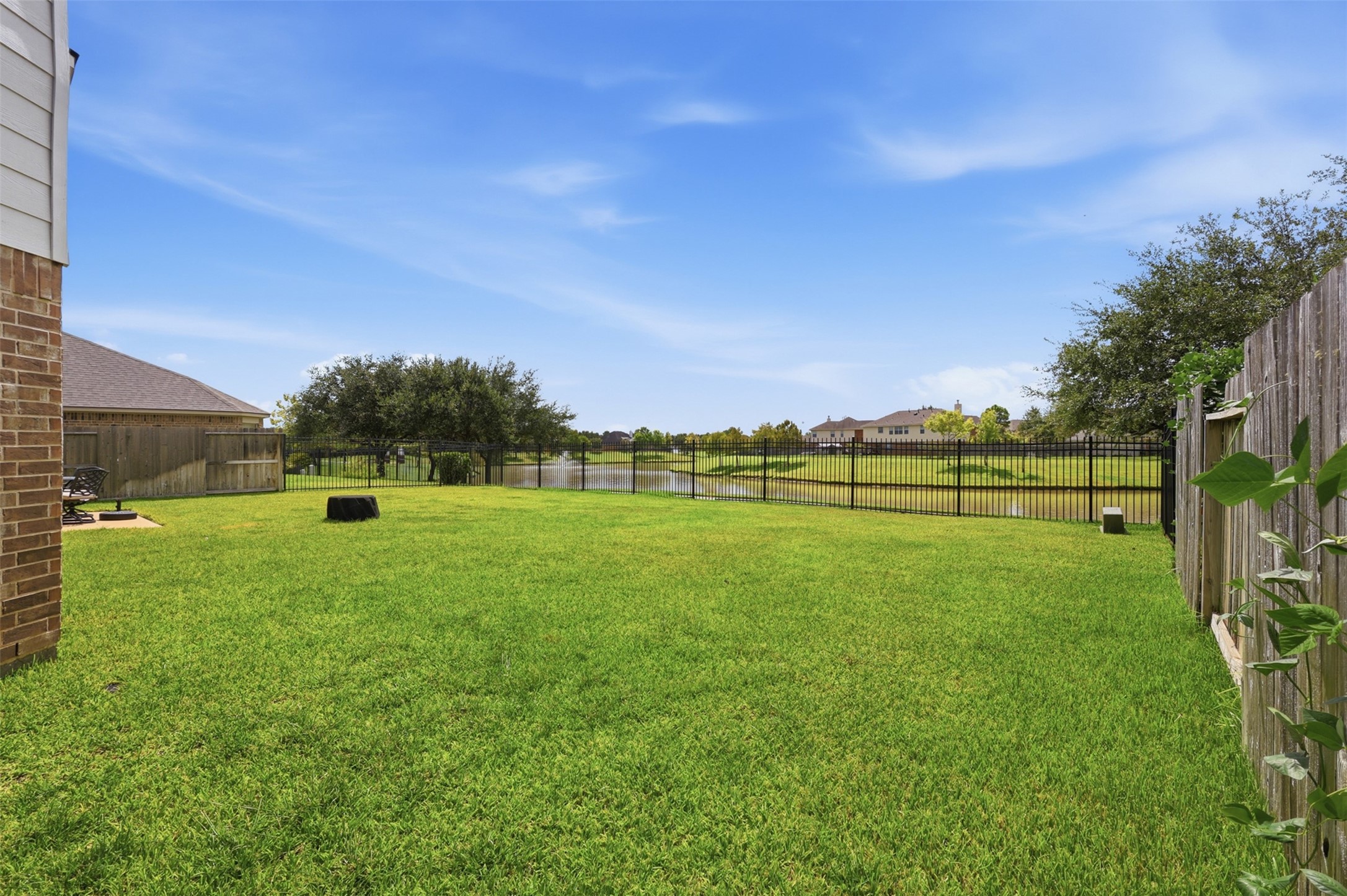 The expansive fenced backyard enjoys open green space with peaceful views toward the neighborhood lake.