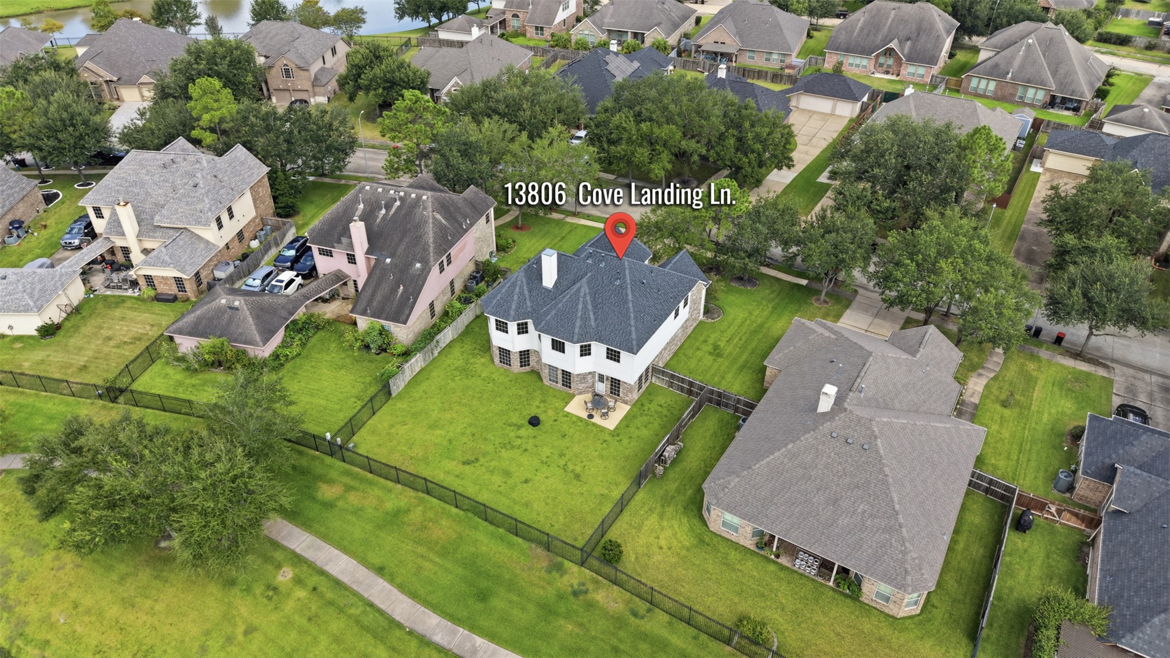 An aerial view highlights the homes generous lot, fenced backyard, and position near the community lake.