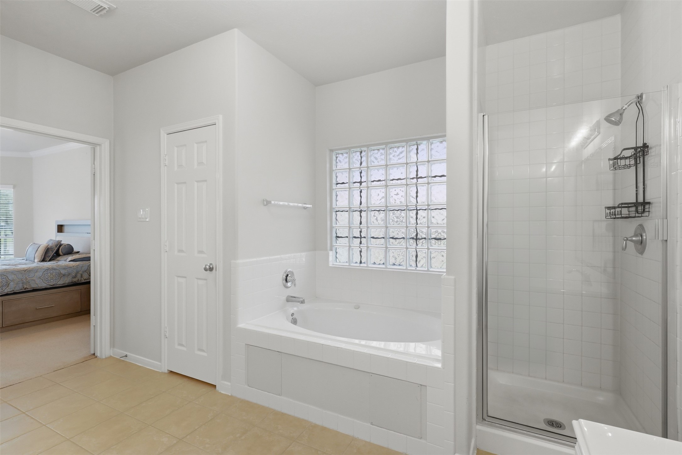 A soaking tub, separate walk-in shower, and glass-block window complete the spacious primary bath.