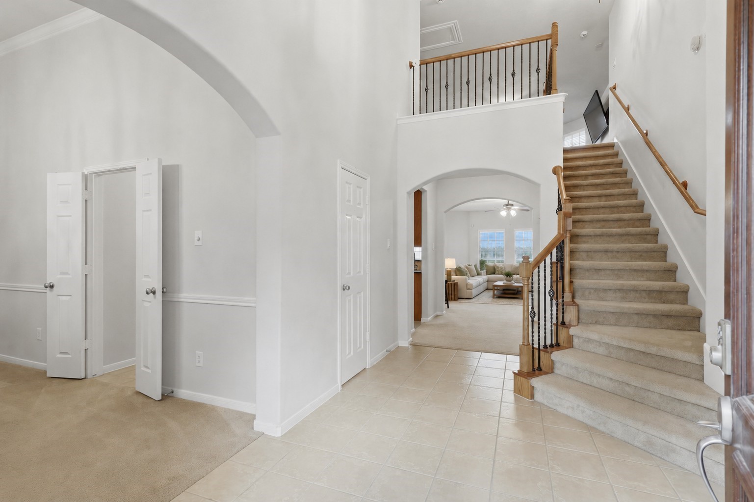 The soaring entryway features an open staircase, tile flooring, and graceful archways connecting the homes main living spaces.