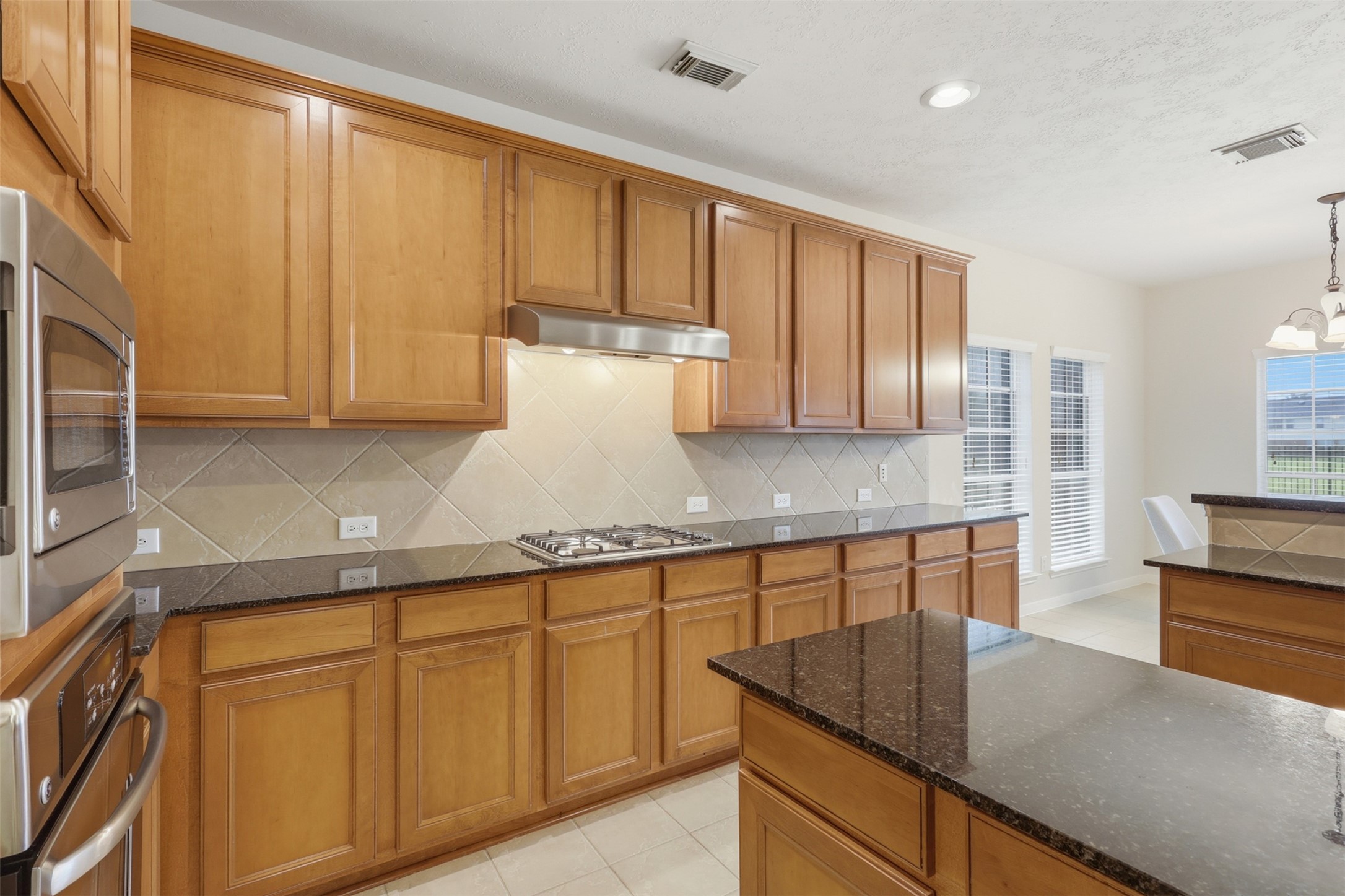 Extensive cabinetry, granite counters, a tile backsplash, and built-in cooking features provide excellent kitchen workspace and storage.
