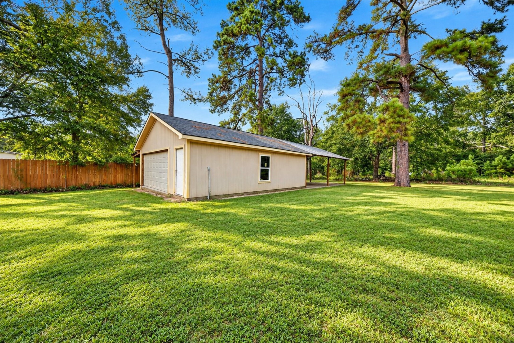 Spacious backyard with mature trees, open green space, and a detached storage building.