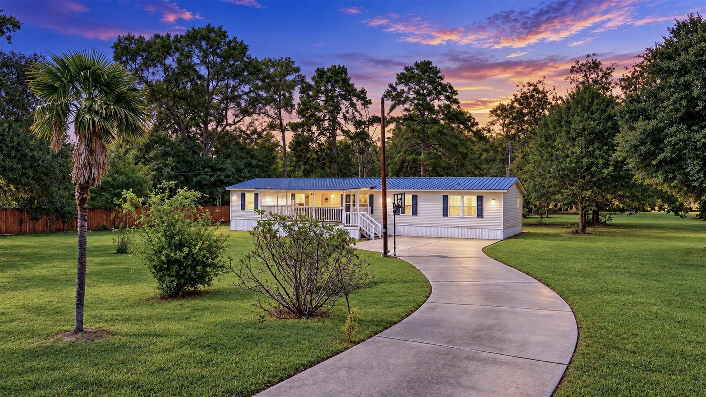 Welcoming exterior view showcasing the homes setting, mature trees, and spacious front lawn.