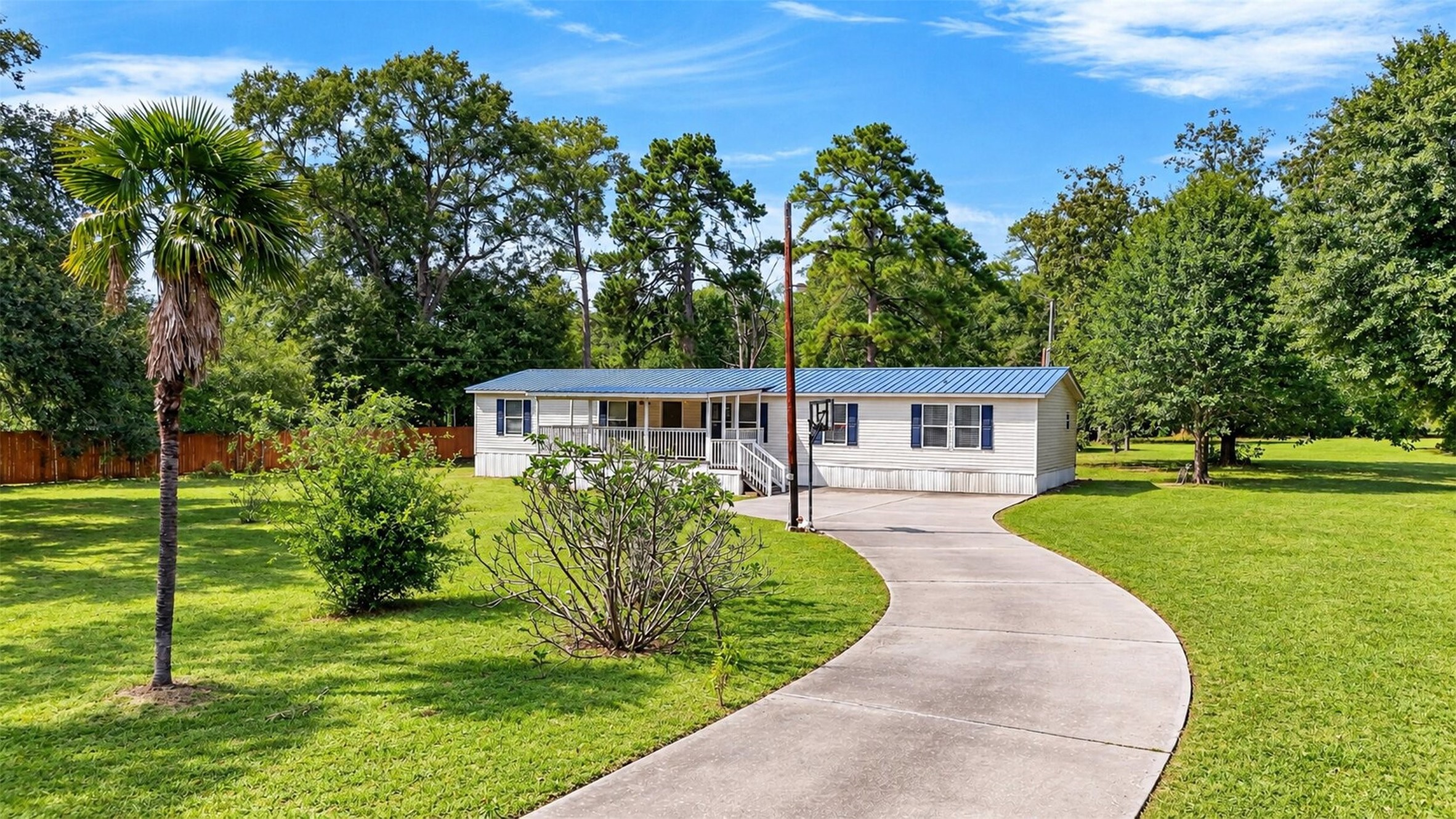 Front view showcasing the long driveway, mature trees, and generous outdoor space.