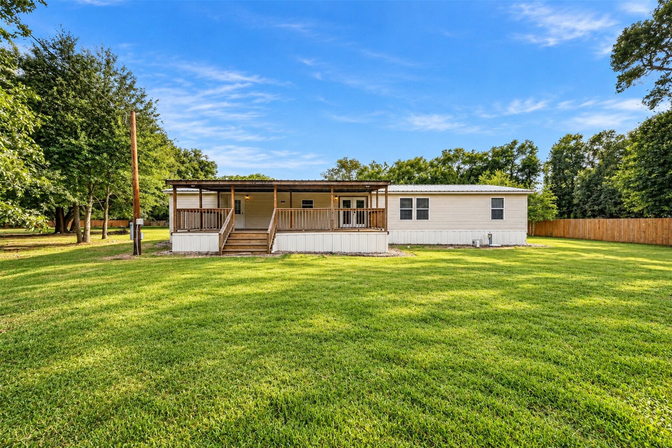 Wide exterior view highlighting the expansive lawn and peaceful, tree lined setting.