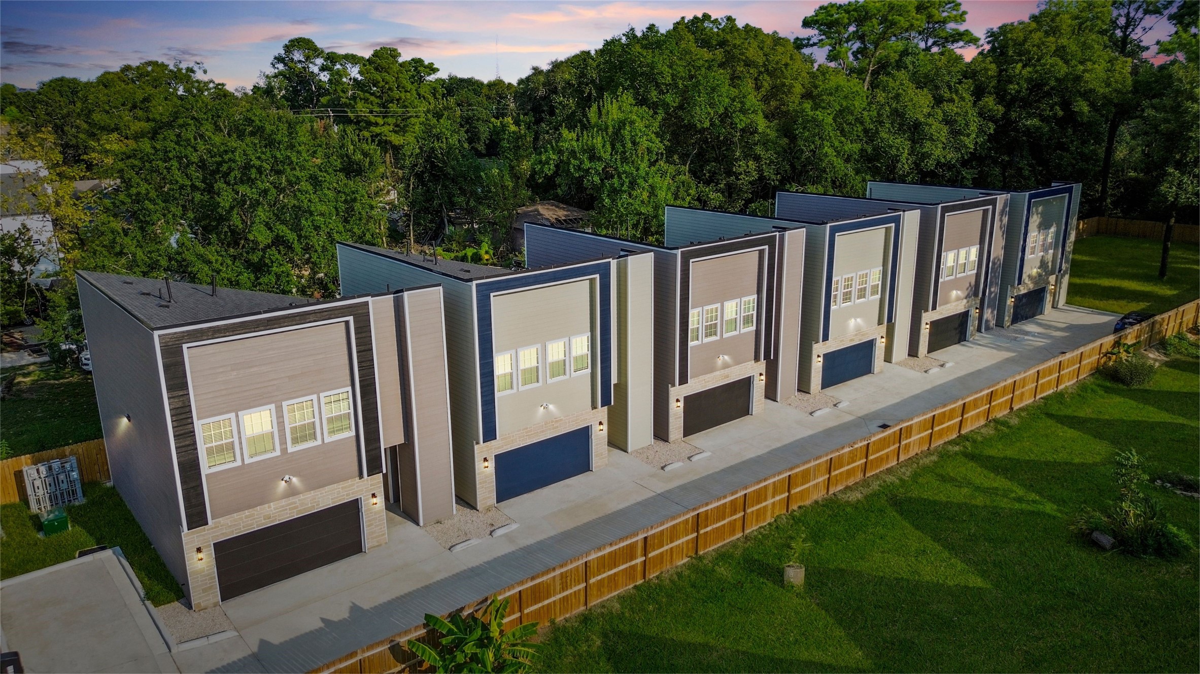From above, you can see the striking row of modern townhomes, each with bold architectural lines and stylish exteriors. The clean, uniform design makes the community feel contemporary and cohesive, while the private fenced backdrop ensures both privacy and peace.