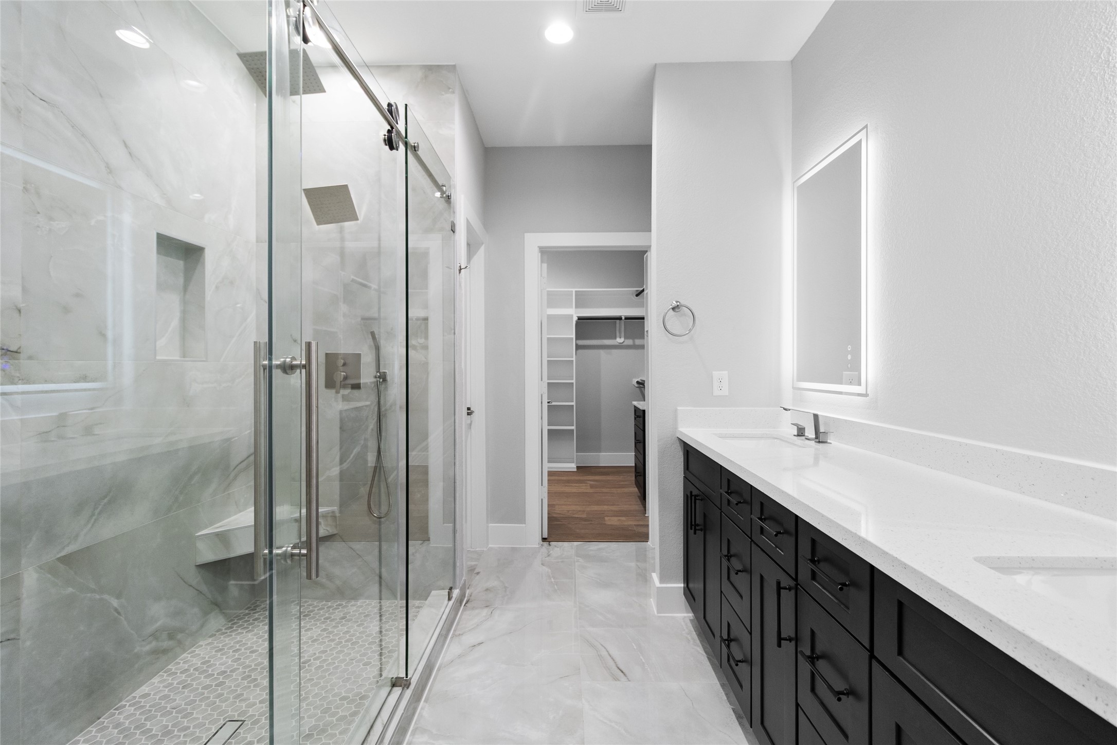 The walk-in shower, framed in glass and marble-style tile, gives you a daily dose of luxury while leading straight into your roomy closet.