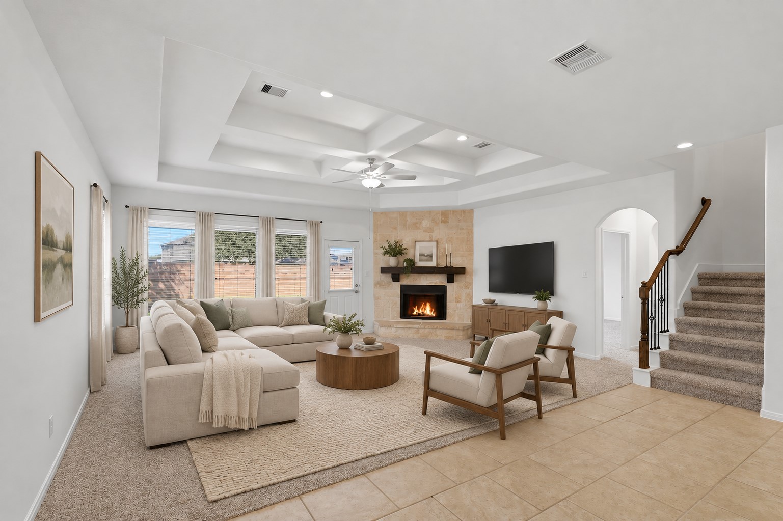 A Beautiful View of the Open Living Space! From this perspective, you can really appreciate the spacious family room, soaring custom ceiling details, stone fireplace, and wall of windows bringing in beautiful natural light. The staircase adds an elegant architectural touch, while the open connection to the kitchen keeps the entire space feeling wonderfully connected. *Photo is virtually staged*