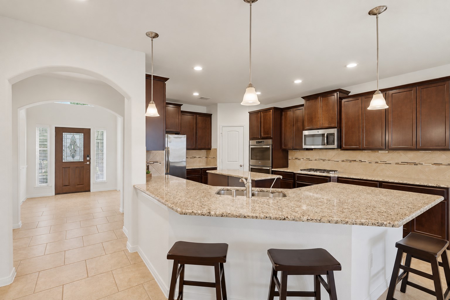 Plenty of Room for Everyone in This Beautiful Kitchen! The generous breakfast bar and oversized granite counters provide wonderful space for casual meals, morning coffee, or visiting with family while dinner is being prepared. Rich custom cabinetry, pendant lighting, and the open layout make this kitchen both beautiful and wonderfully functional.