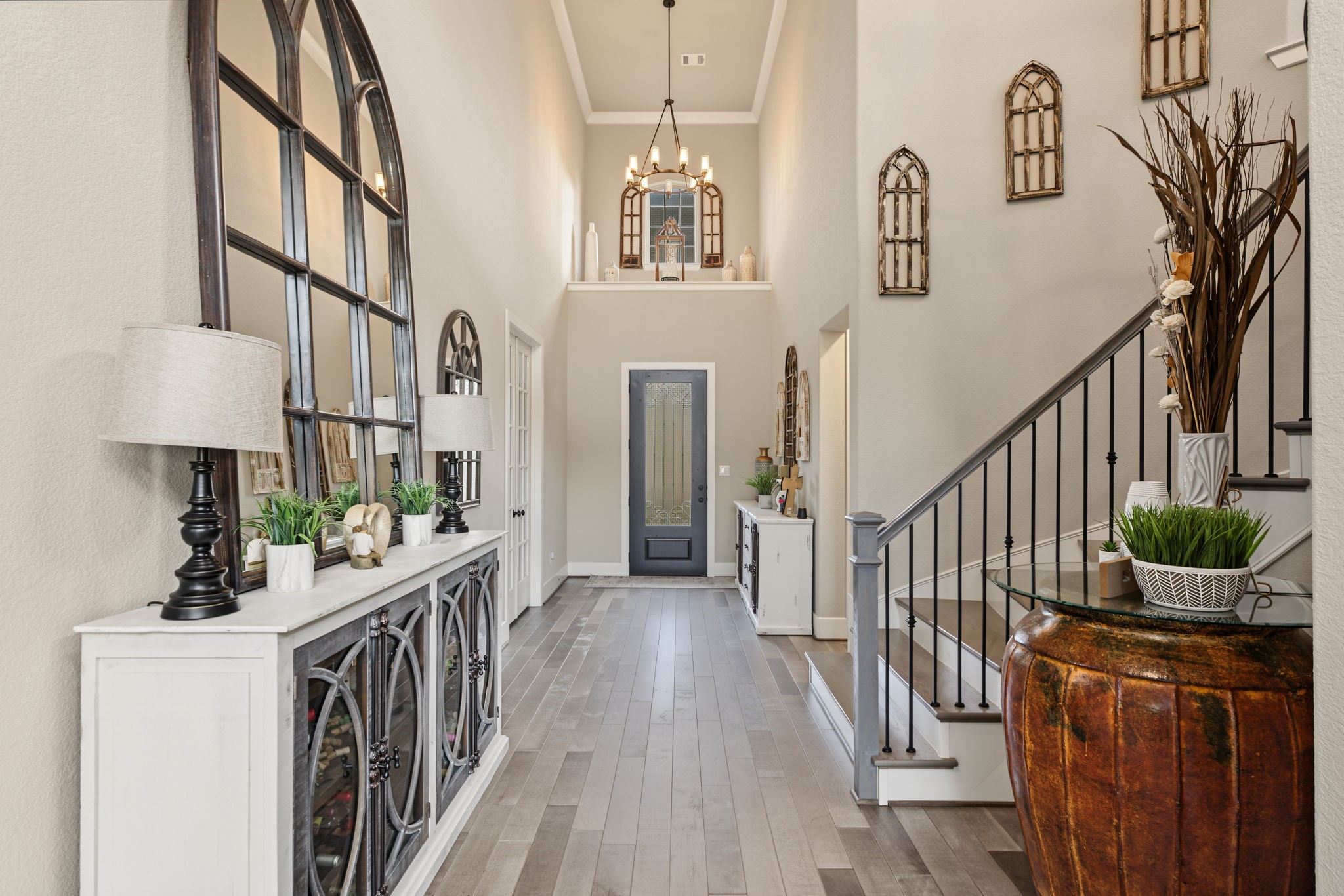 Another beautiful view of the impressive entryway featuring a striking staircase, decorative iron railing, and elegant chandelier. Another beautiful view of the impressive entryway featuring a striking staircase, decorative iron railing, and elegant chandelier.