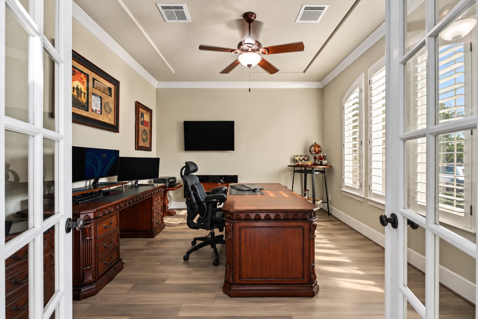 Elegant Private Home Office! Dedicated study featuring French doors, a tray ceiling, and large windows with plantation shutters, perfect for working from home.