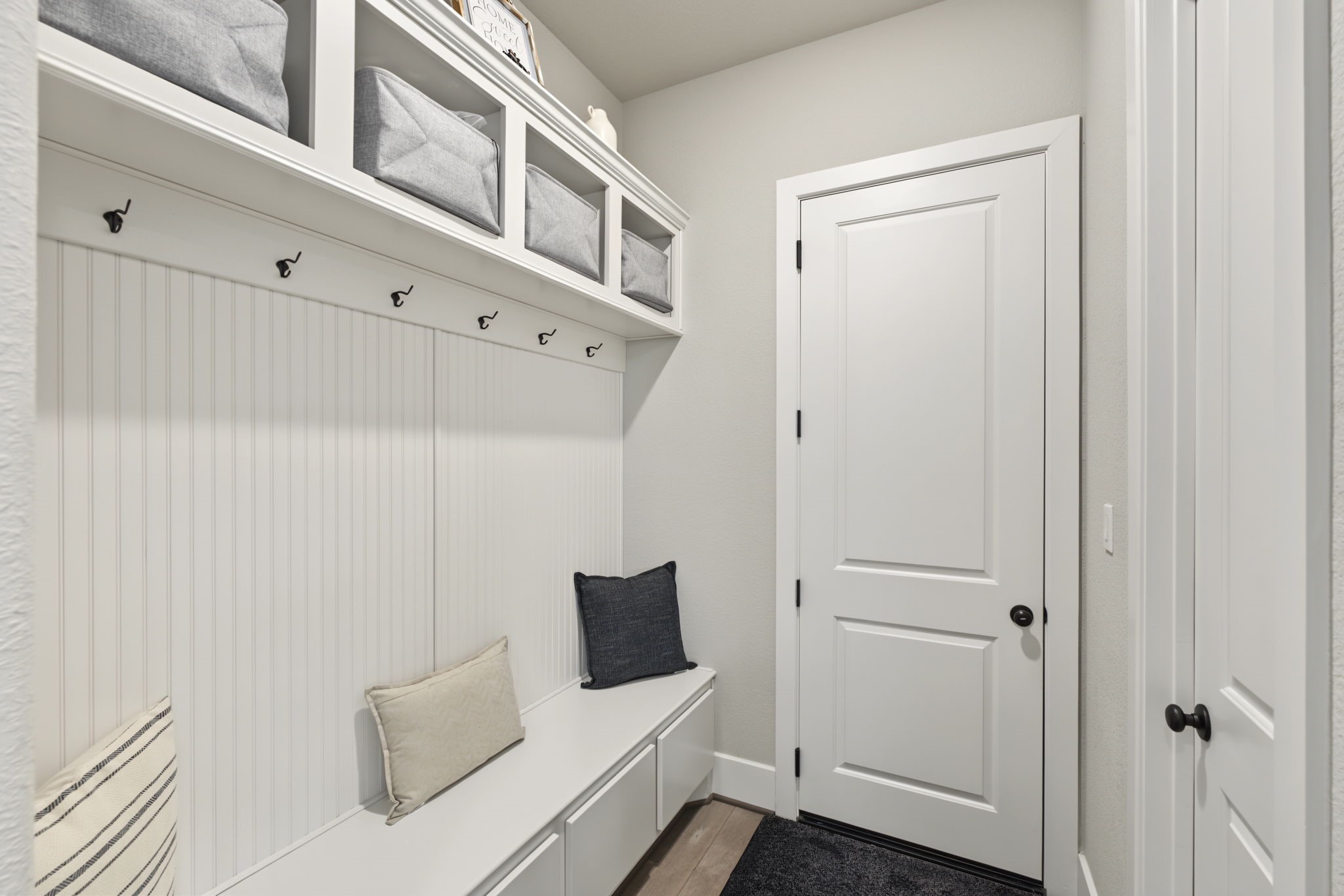 Convenient mudroom featuring built-in cabinetry, storage cubbies, hooks, and a bench to keep everyday essentials organized.