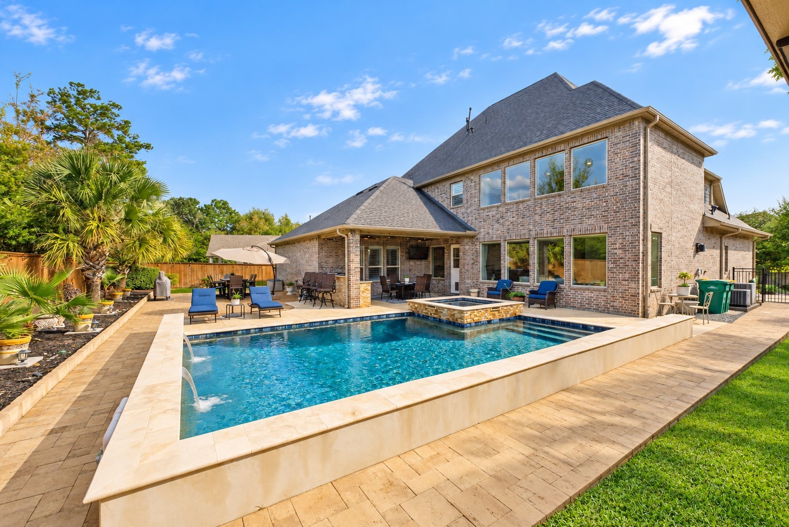 Exceptional outdoor living space featuring a sparkling pool, comfortable lounging areas, tropical landscaping, and plenty of room for entertaining!