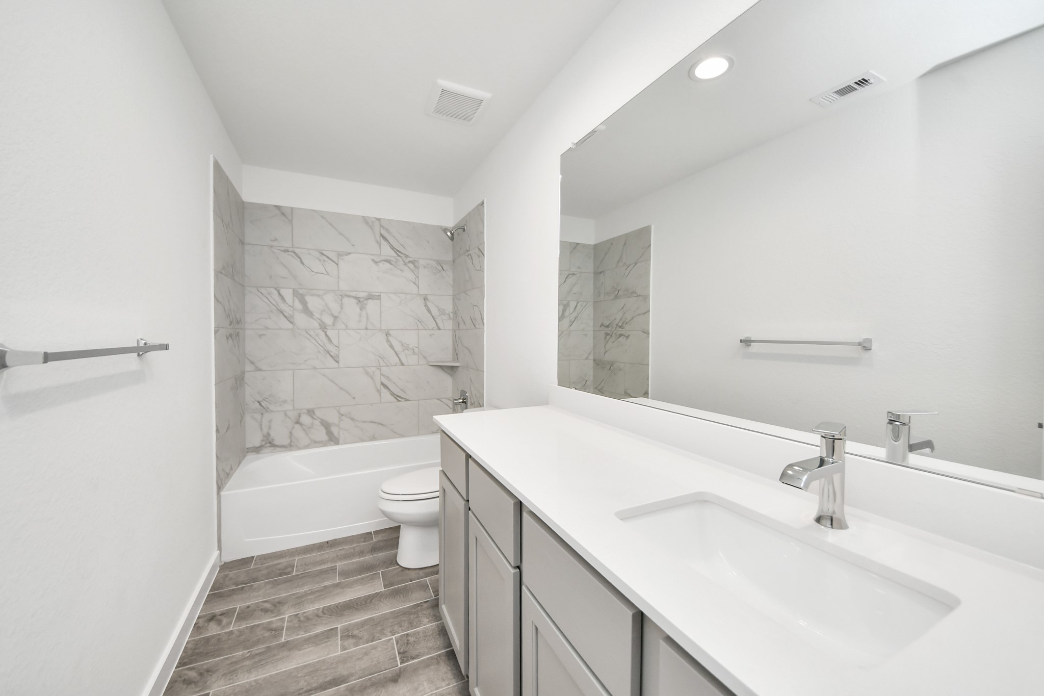 Secondary bath features tile flooring, bath/shower combo with tile surround, light stained wood cabinets, beautiful light countertop. Sample photo of completed home with similar floor plan. Actual colors and selections may vary.