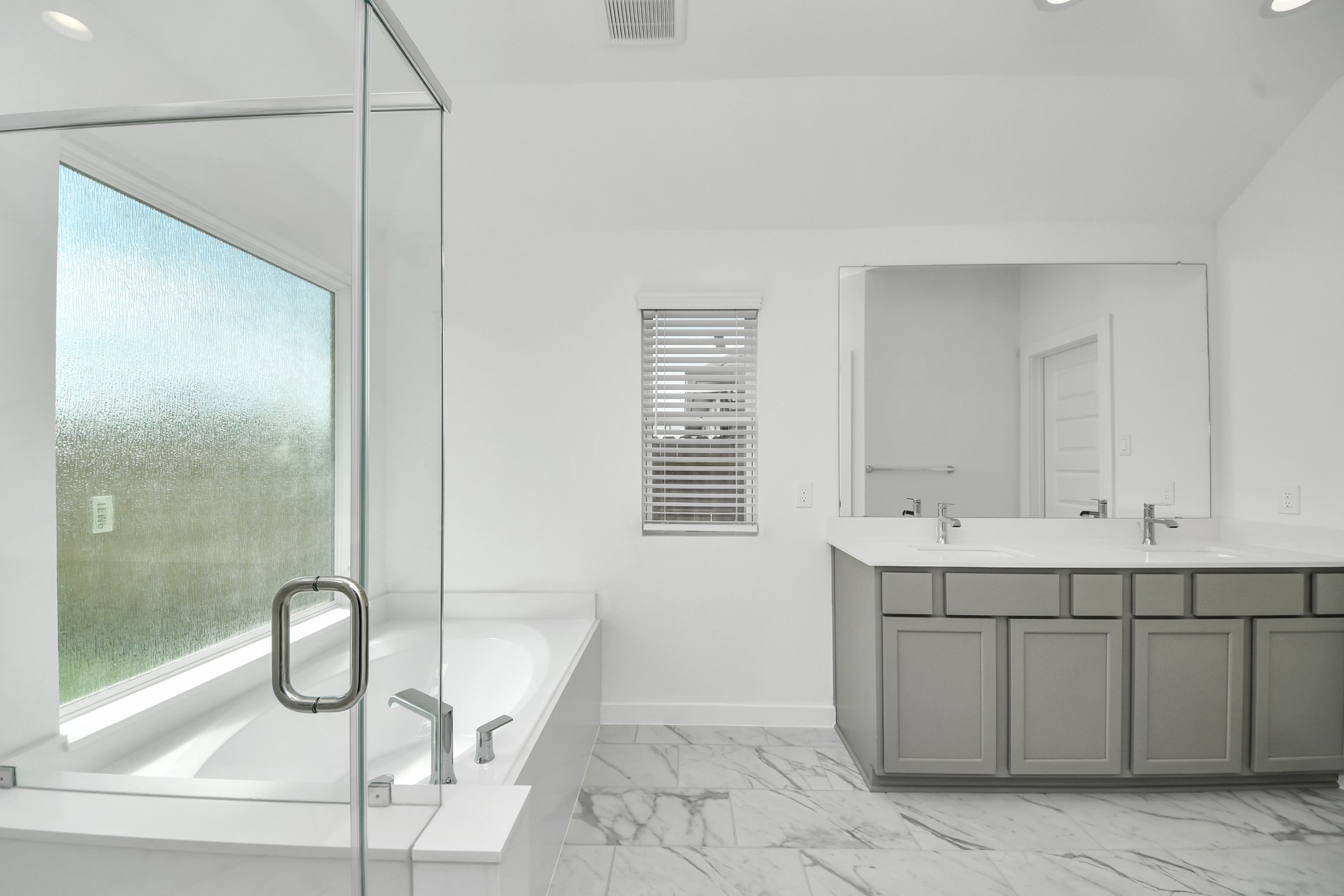 Indulge in a spa-like retreat within the confines of this primary bathroom. Delight in a spacious walk-in shower enveloped in stylish tile surround, unwind in a separate garden tub adorned with custom detailing. Sample photo of completed home with similar floor plan. Actual colors and selections may vary.