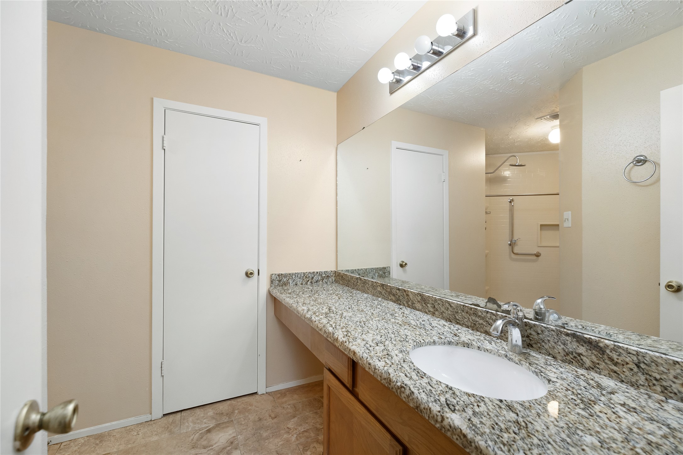 Primary bath, showing door to walk-in closet and granite counters