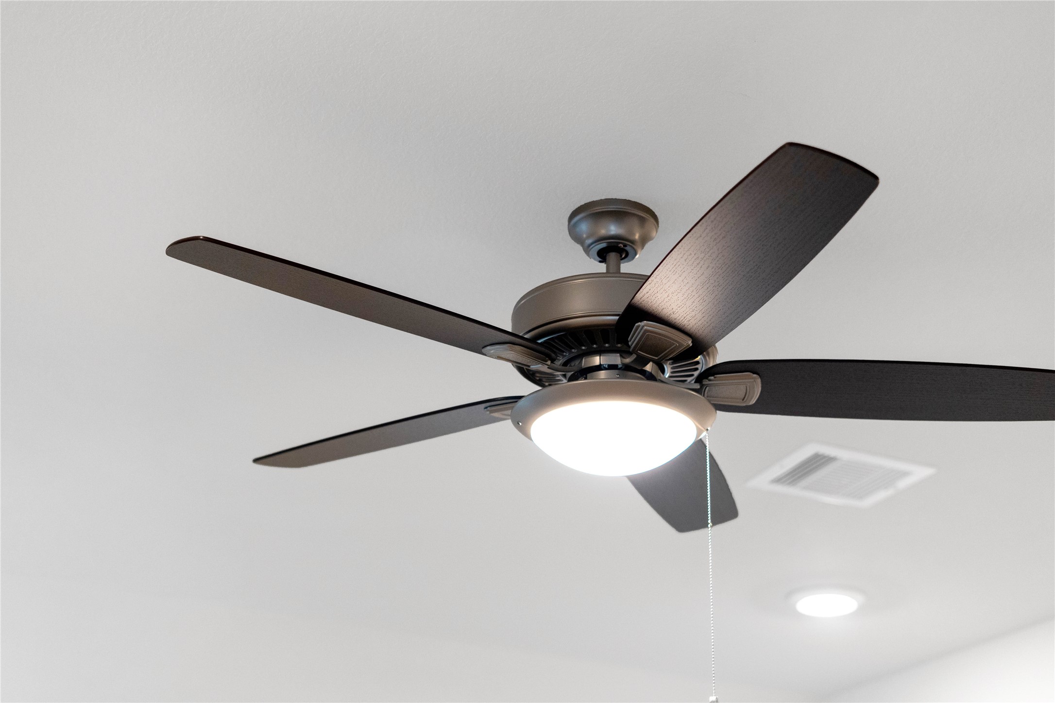 This contemporary ceiling fan features a brushed nickel finish and five dark wood blades, centered by an integrated LED light kit and a traditional pull chain for effortless control. The ceiling fan will make a room feel up to 48 degrees cooler and redistribute rising warm air in the winter.