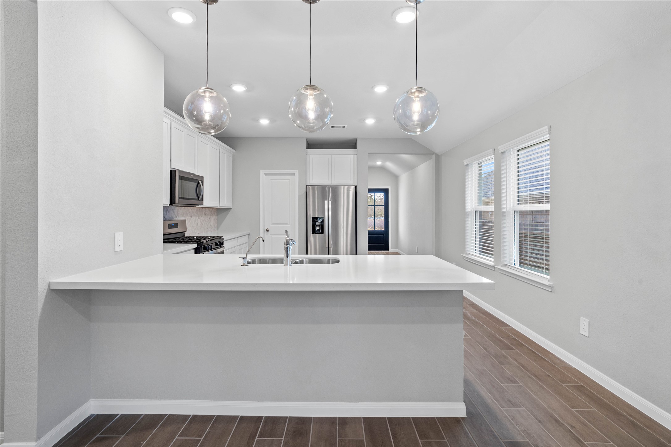 The expansive quartz-topped counter stands as the home's true heartbeat, offering a natural gathering spot where family and friends naturally gravitate to share meals, conversation, and connection.