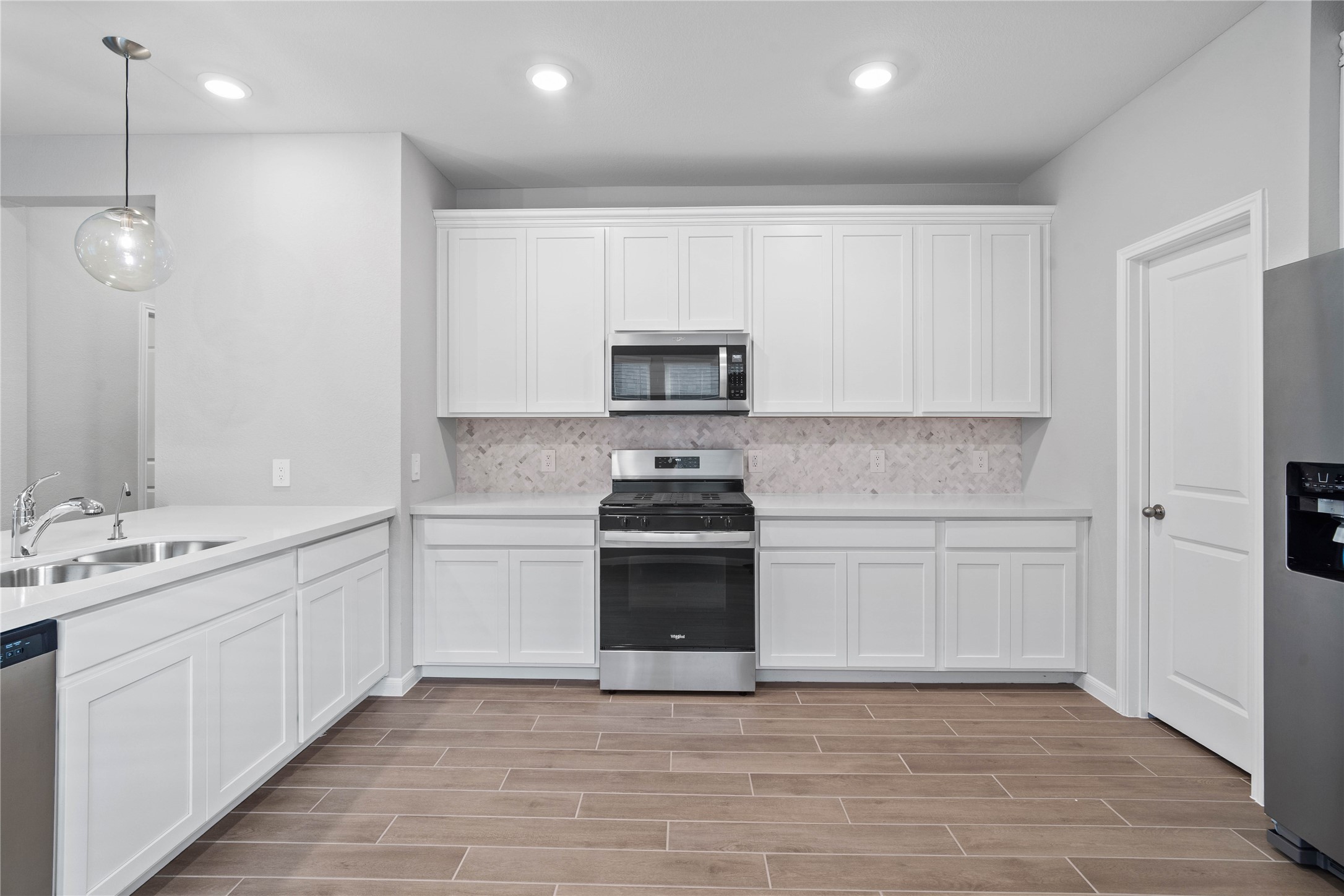 Expansive countertops provide a clean, horizontal sweep that beautifully highlights the intricate patterns of the Mosaix Daphne White Herringbone backsplash.