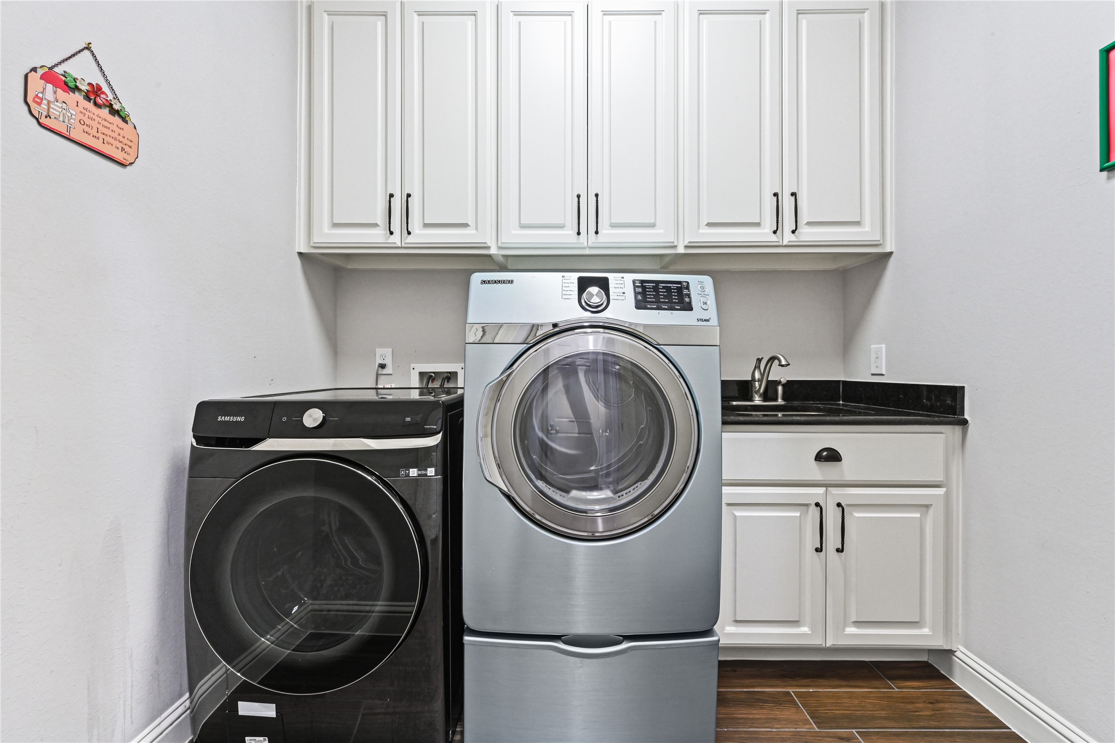 Just beyond the gourmet kitchen, discover a beautifully designed custom laundry room tucked away from the main living areas! Featuring tall custom cabinets for exceptional storage, a convenient utility sink surrounded by gorgeous granite countertops & plenty of workspace. Even the laundry room has been thoughtfully designed with style, function & custom details!