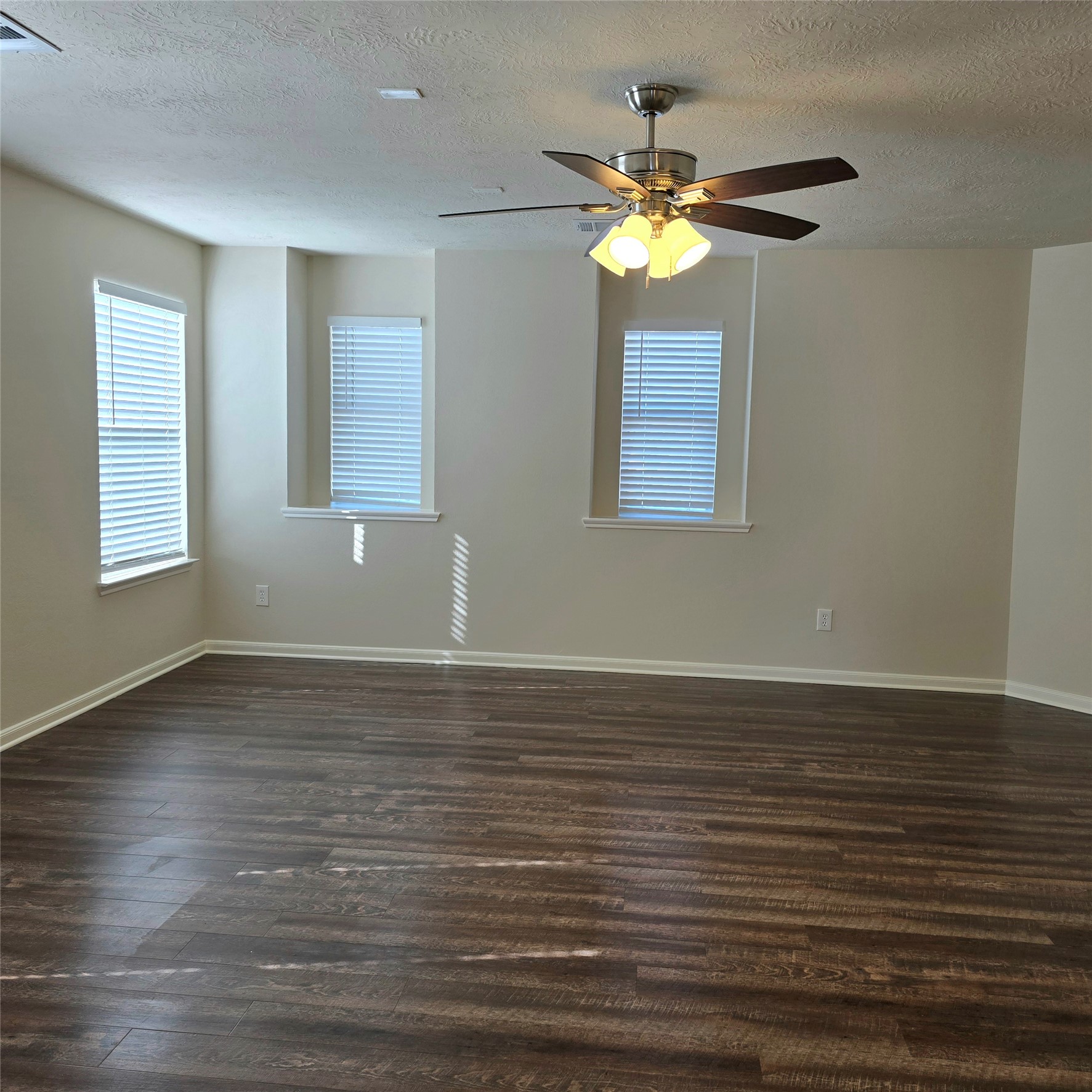 Large den with lots of natural light and ceiling fan with light fixtures.