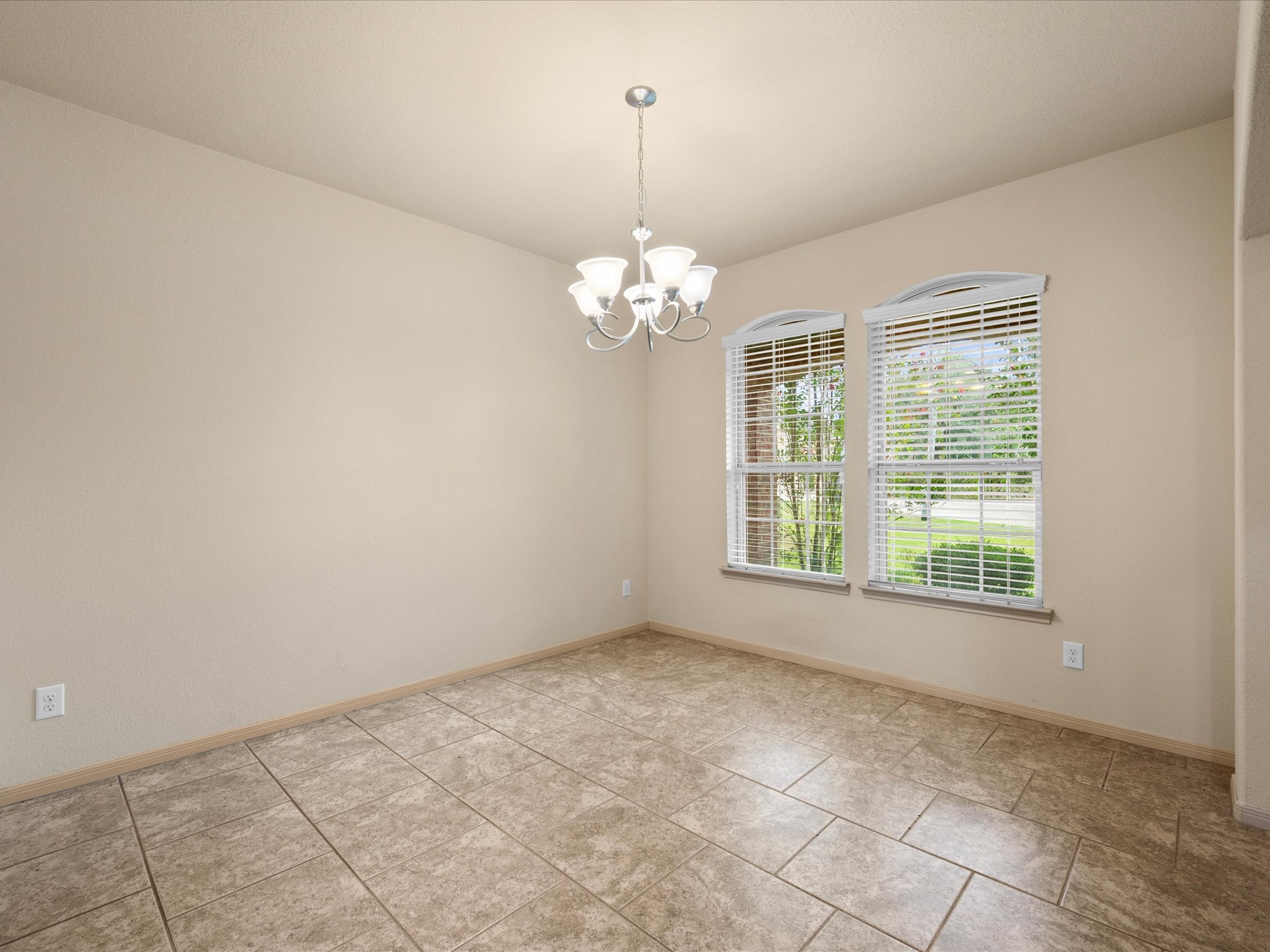 Versatile formal dining room located off the main entry, complete with a traditional light fixture, tile flooring, and large windows with blinds for great natural lighting. Perfect as a dedicated dining space or a home office/study.